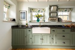 sage green cupboards with a large ceramic sink