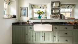 sage green cupboards with a large ceramic sink
