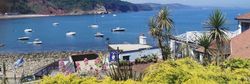 Boats anchored in Babbacombe Bay with coastal gardens and Cary Arms buildings in the foreground on a sunny day in South Devon