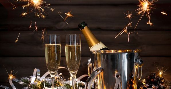 Champagne bottle in ice bucket with two glasses, sparklers, and festive decorations