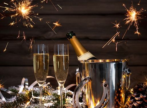 Champagne bottle in ice bucket with two glasses, sparklers, and festive decorations