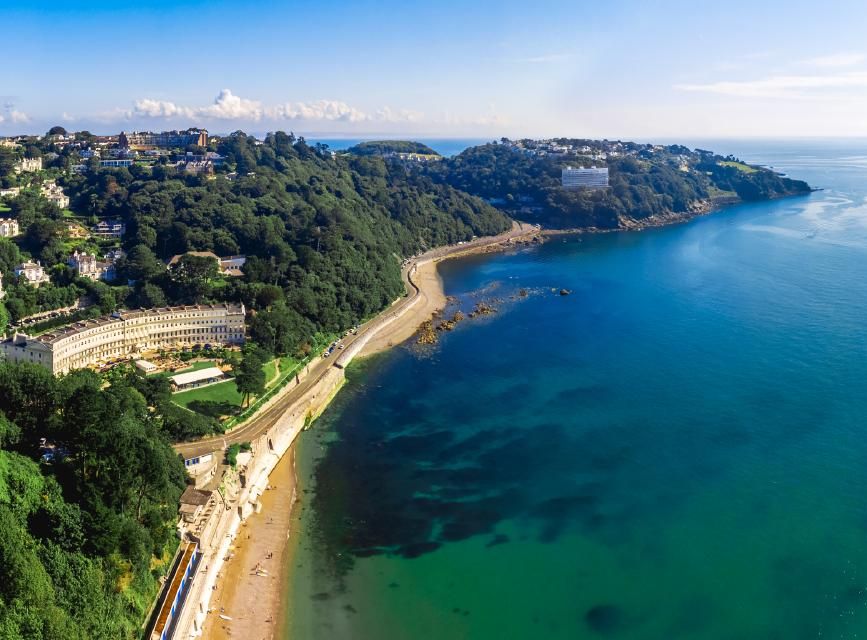 Aerial view of Meadfoot Beach and surrounding coastline with lush greenery and blue sea.