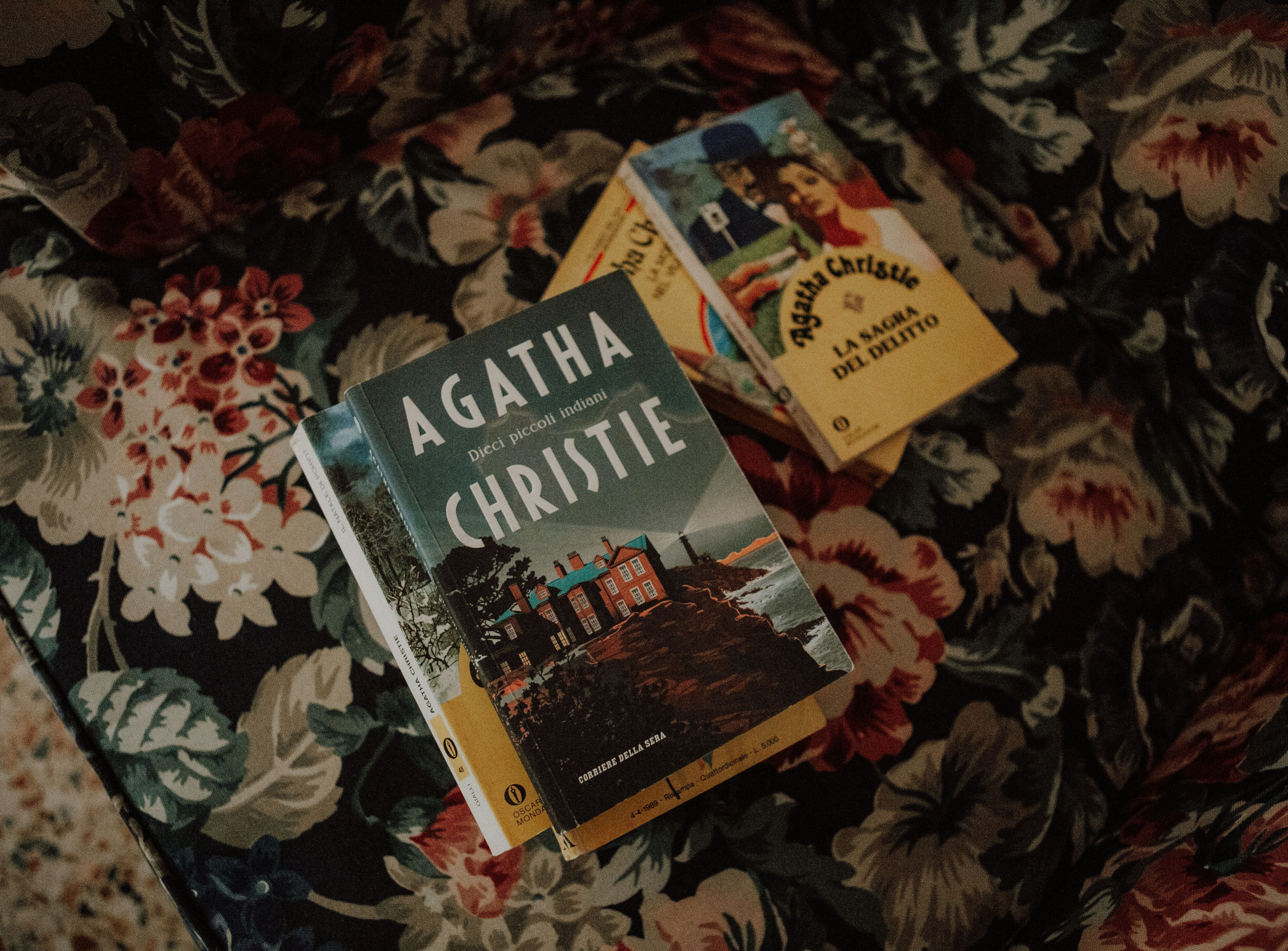 Three Agatha Christie books on a floral upholstered surface