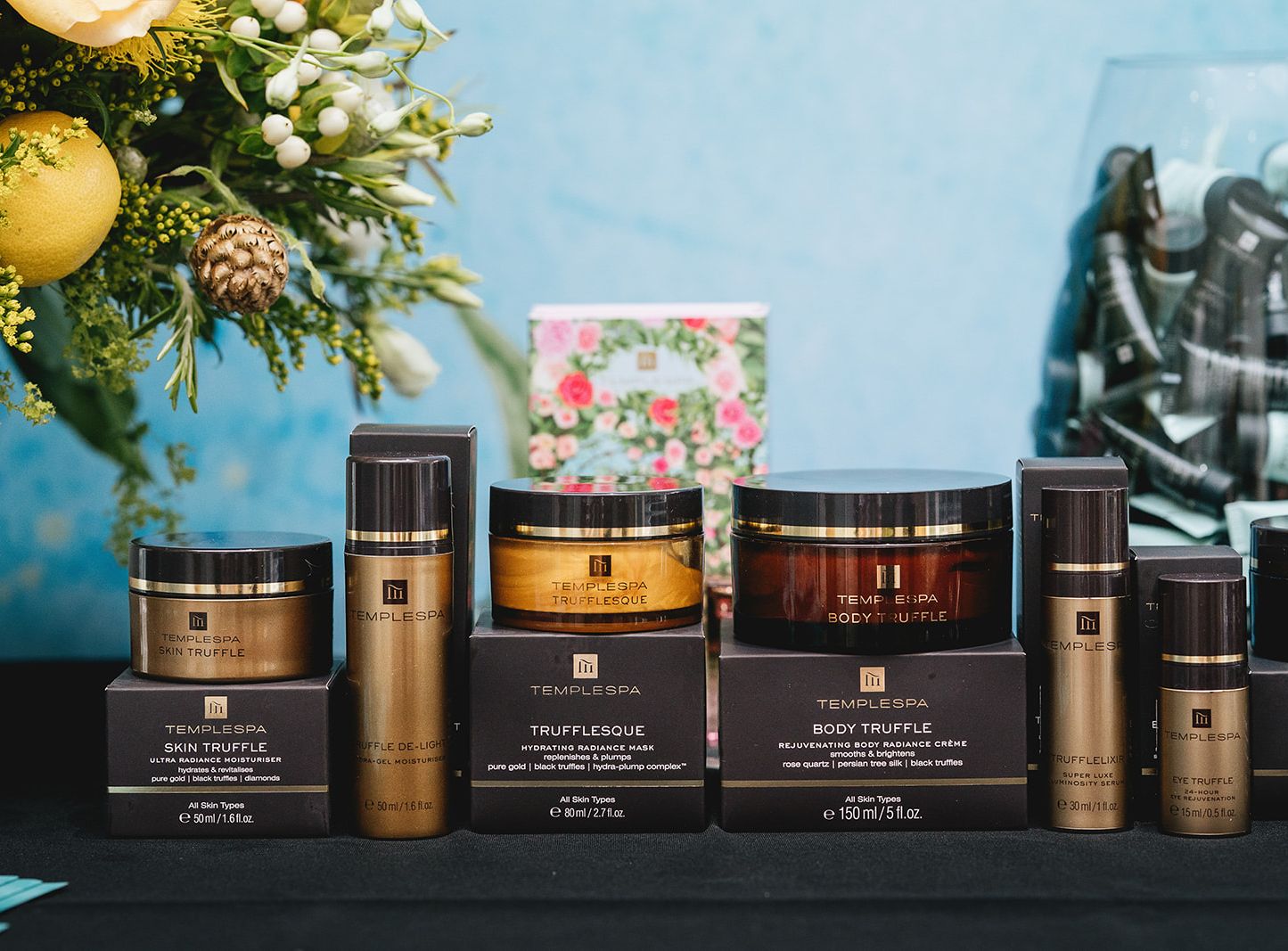 Temple Spa skincare products displayed on a table with flowers in the background.