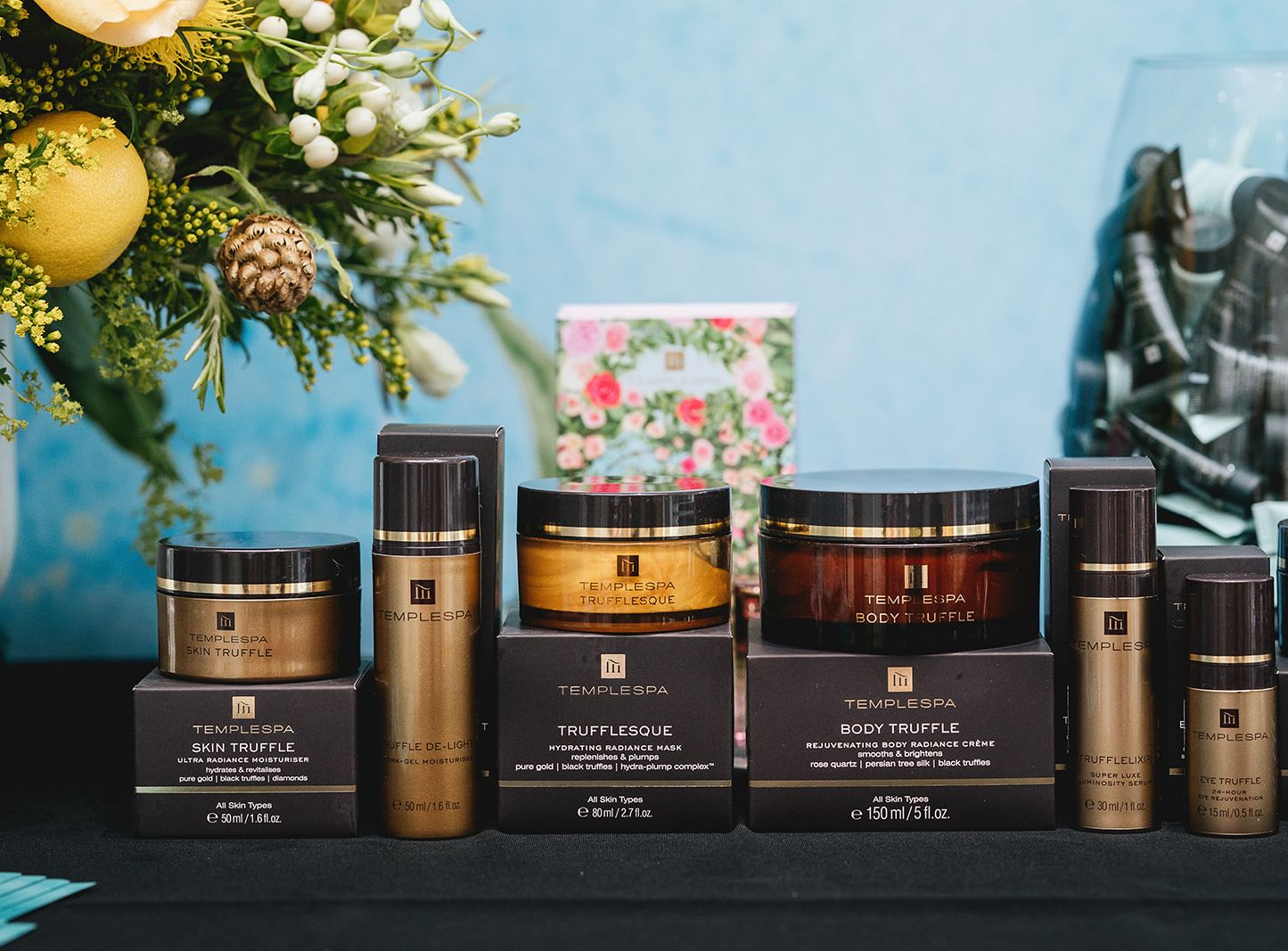 Temple Spa skincare products displayed on a table with flowers in the background.