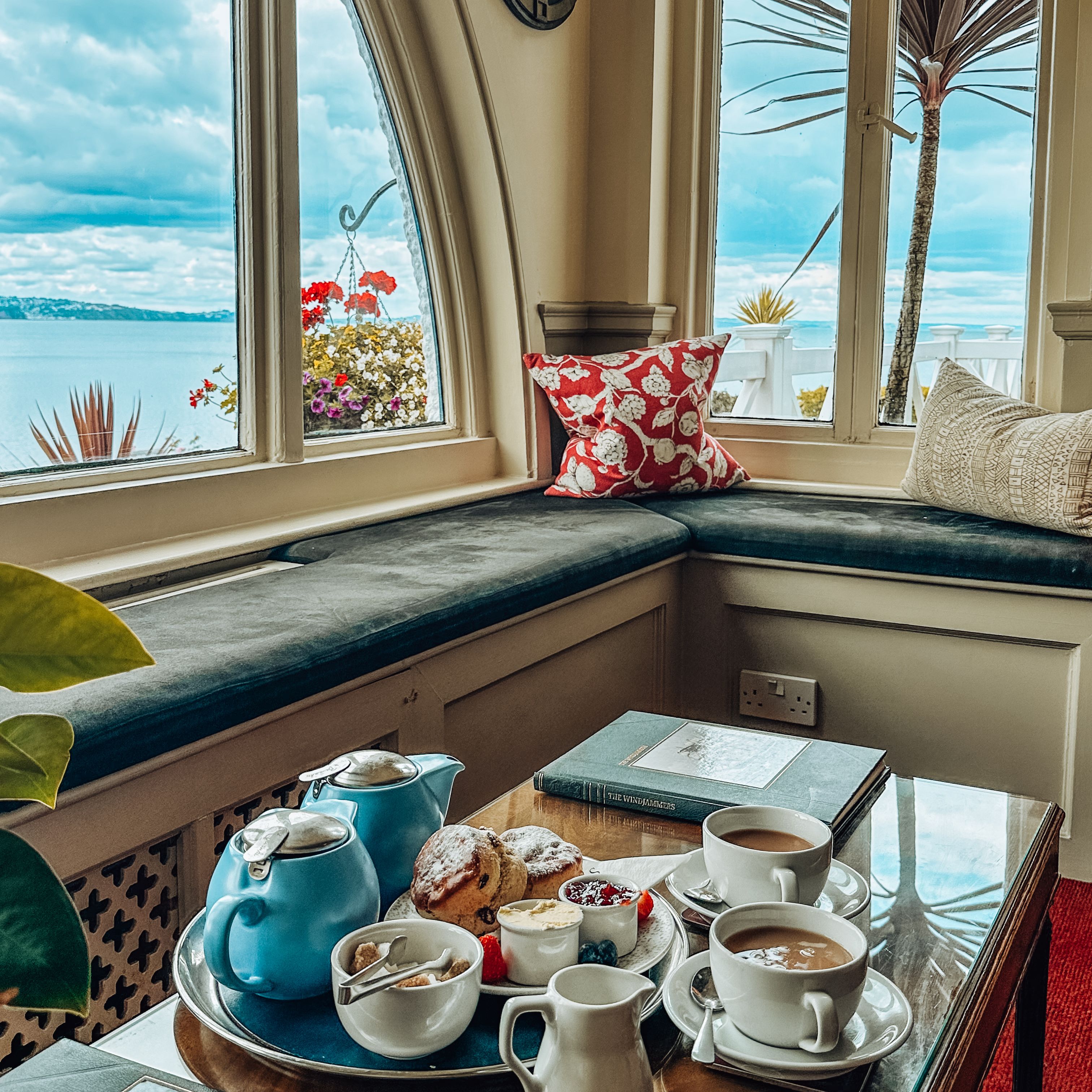Cozy tea setup with pastries by a window overlooking the sea