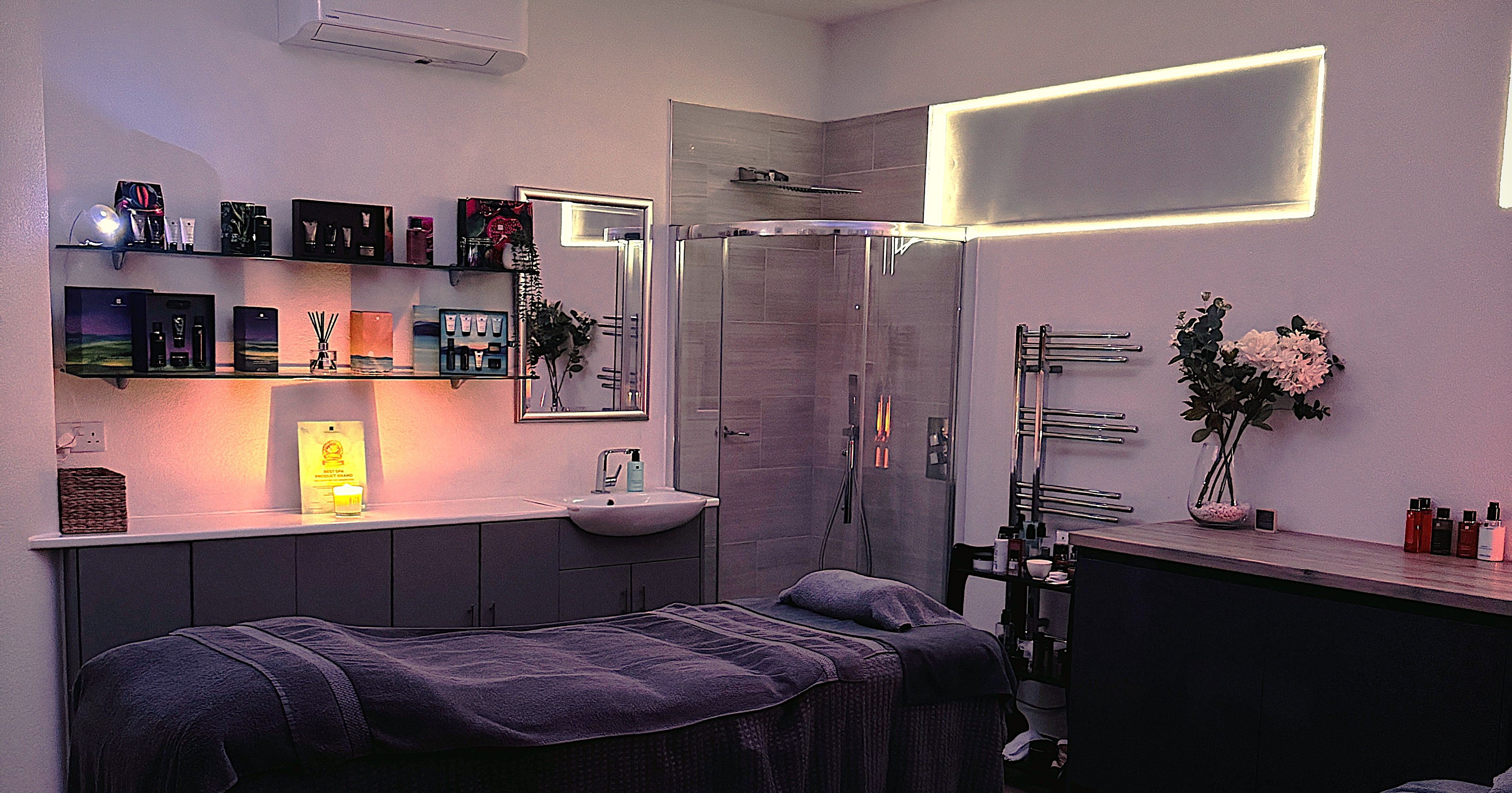 A tranquil spa room with two massage tables, dim lighting, and colorful lights reflected on the ceiling.
