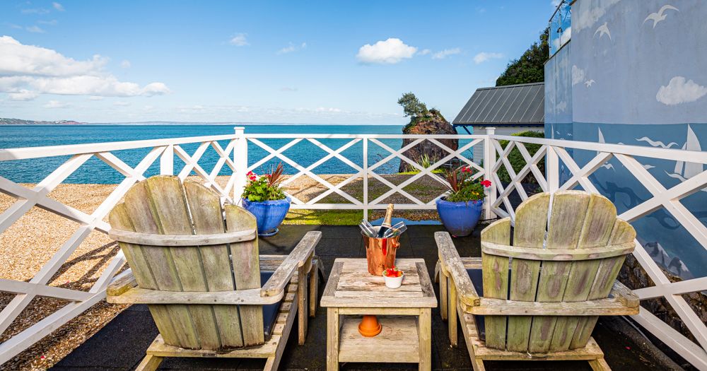 Two wooden chairs on a seaside terrace overlooking the ocean under a blue sky