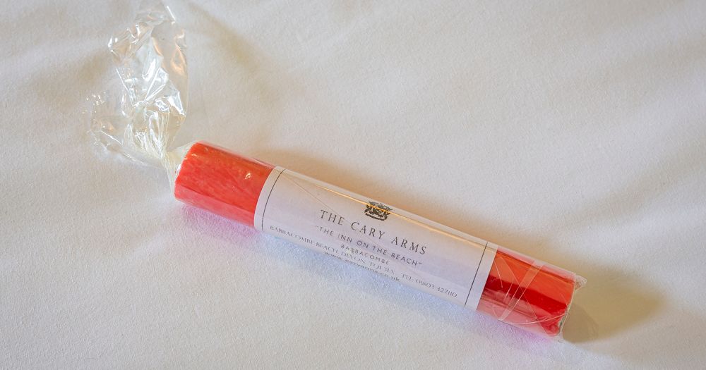 Wrapped red beach bag on a white bed sheet
