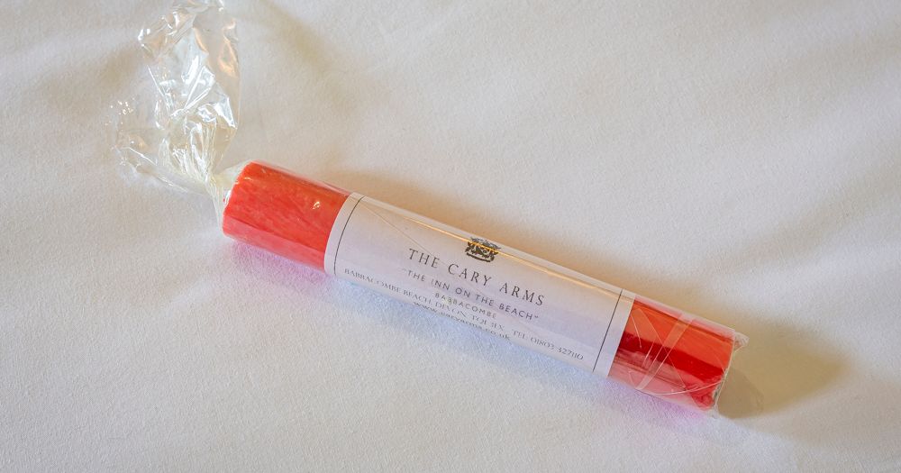 Wrapped red beach bag on a white bed sheet