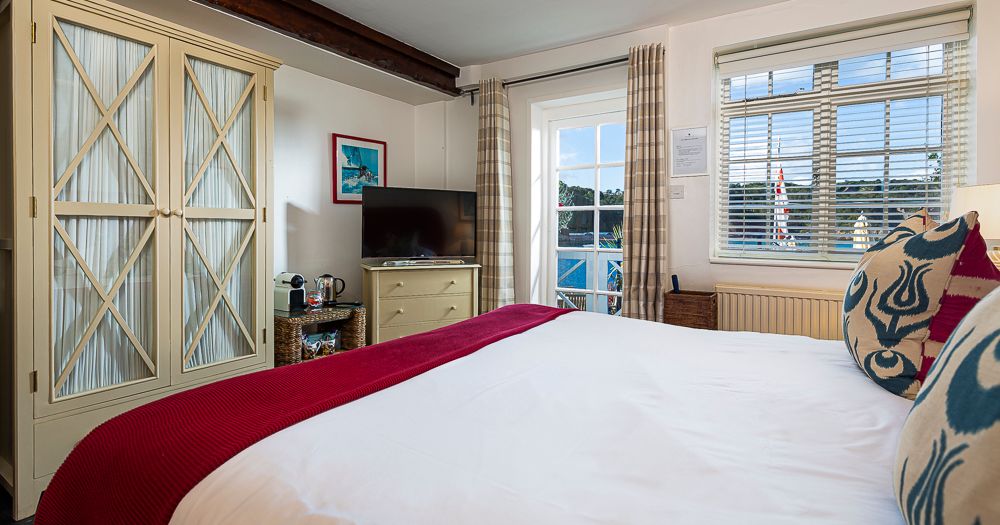 Cosy bedroom with double bed, cream wardrobe, TV and window blinds