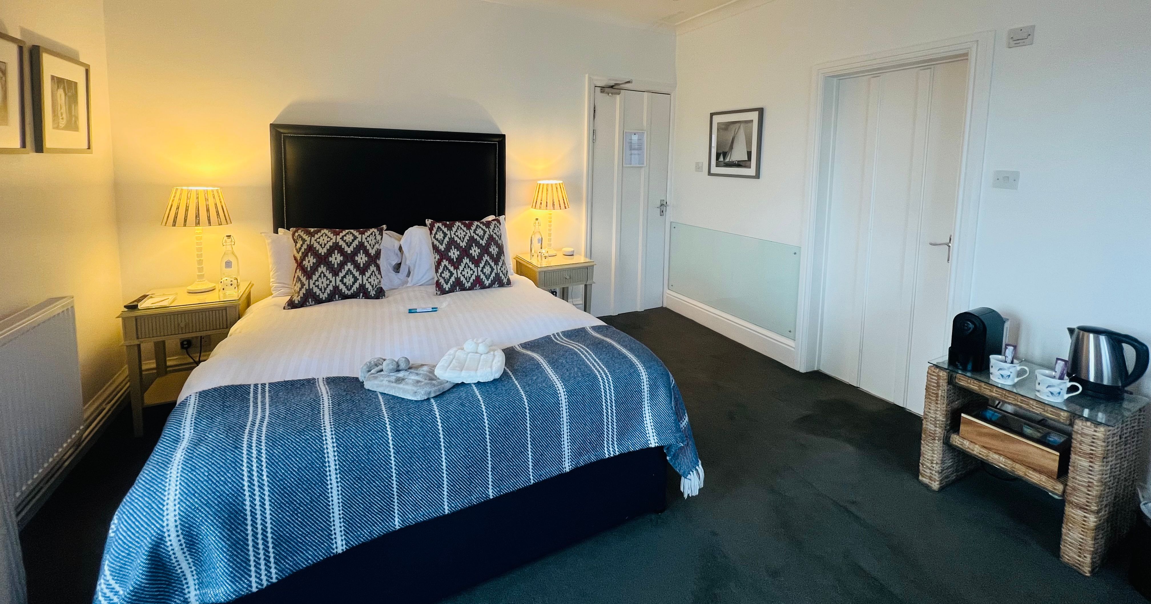 Cosy double bedroom with black headboard, bedside lamps and blue striped throw