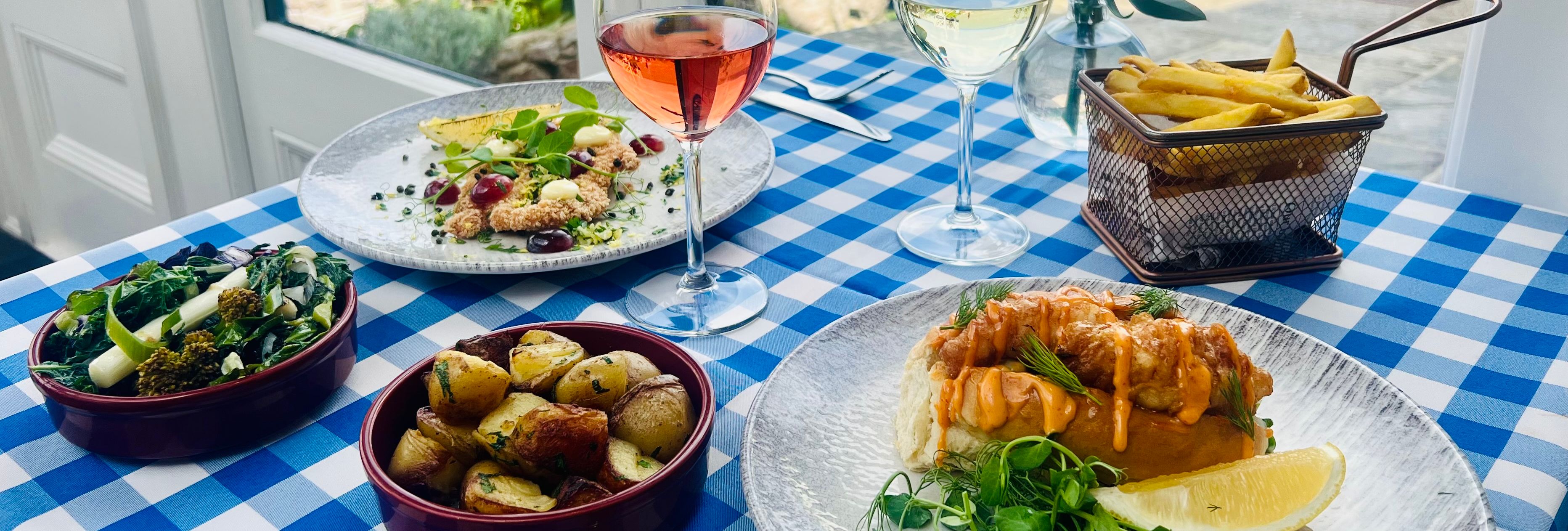 Seafood meal with wine on a blue-and-white checkered table by a window overlooking the sea