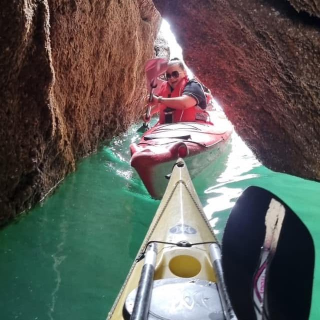 Kayakers paddling through a narrow rock passage in turquoise water