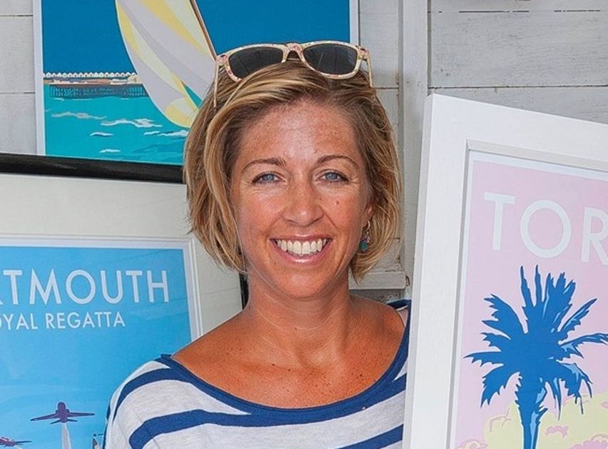 Smiling woman in a striped top holding framed artwork