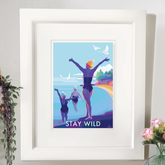 Framed art print of a colourful beach scene with swimmers and the words 