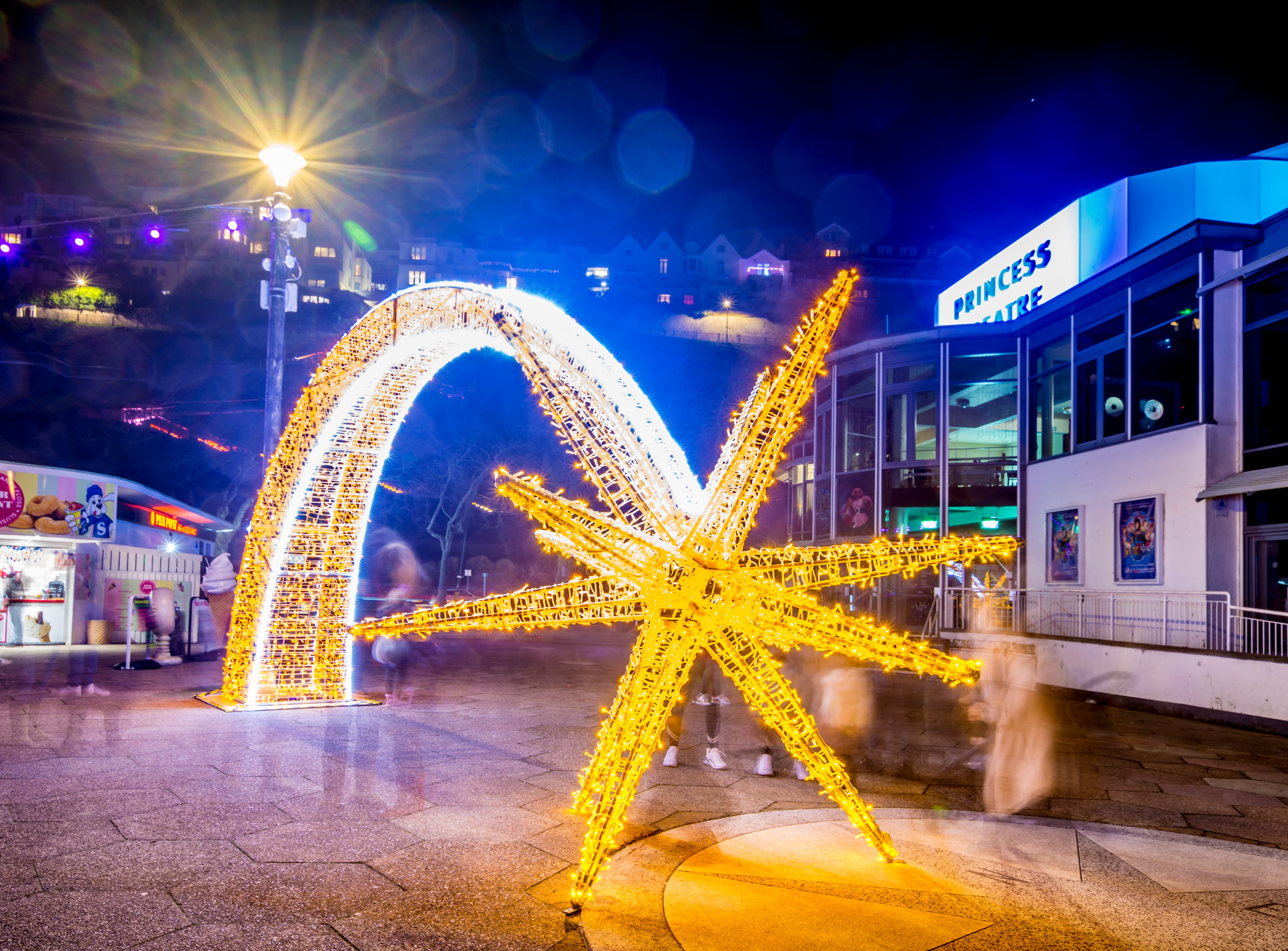 Illuminated golden starfish and arch light display outside the Princess Theatre at night