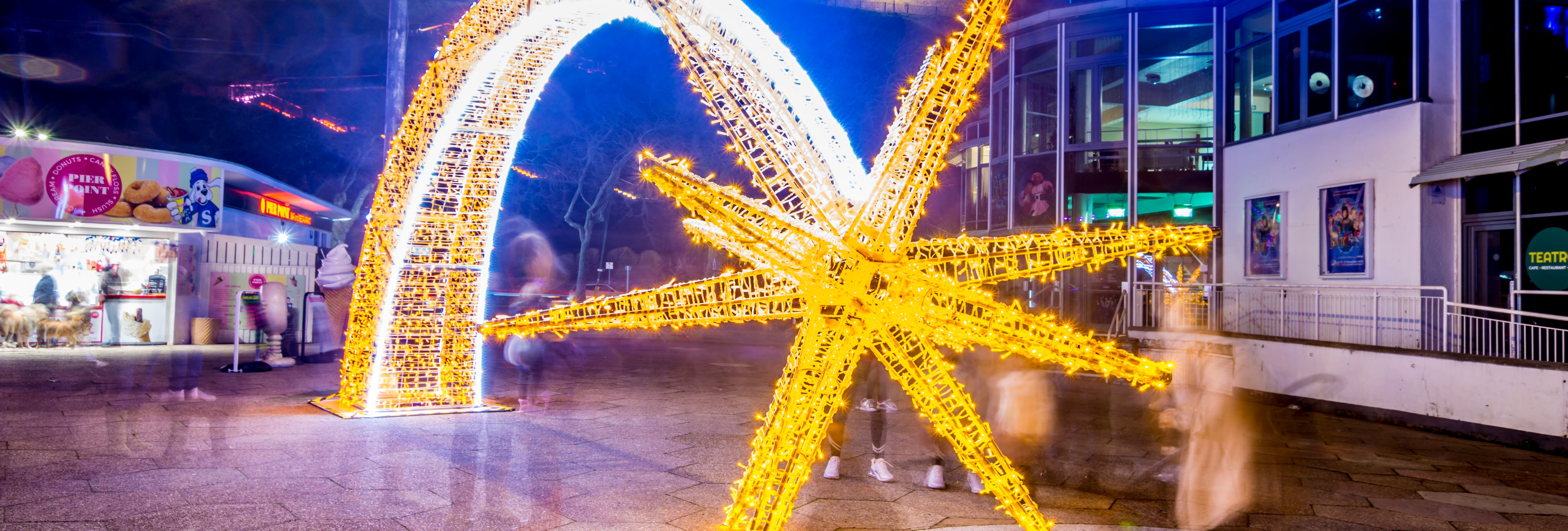 Illuminated golden starfish and arch light display outside the Princess Theatre at night