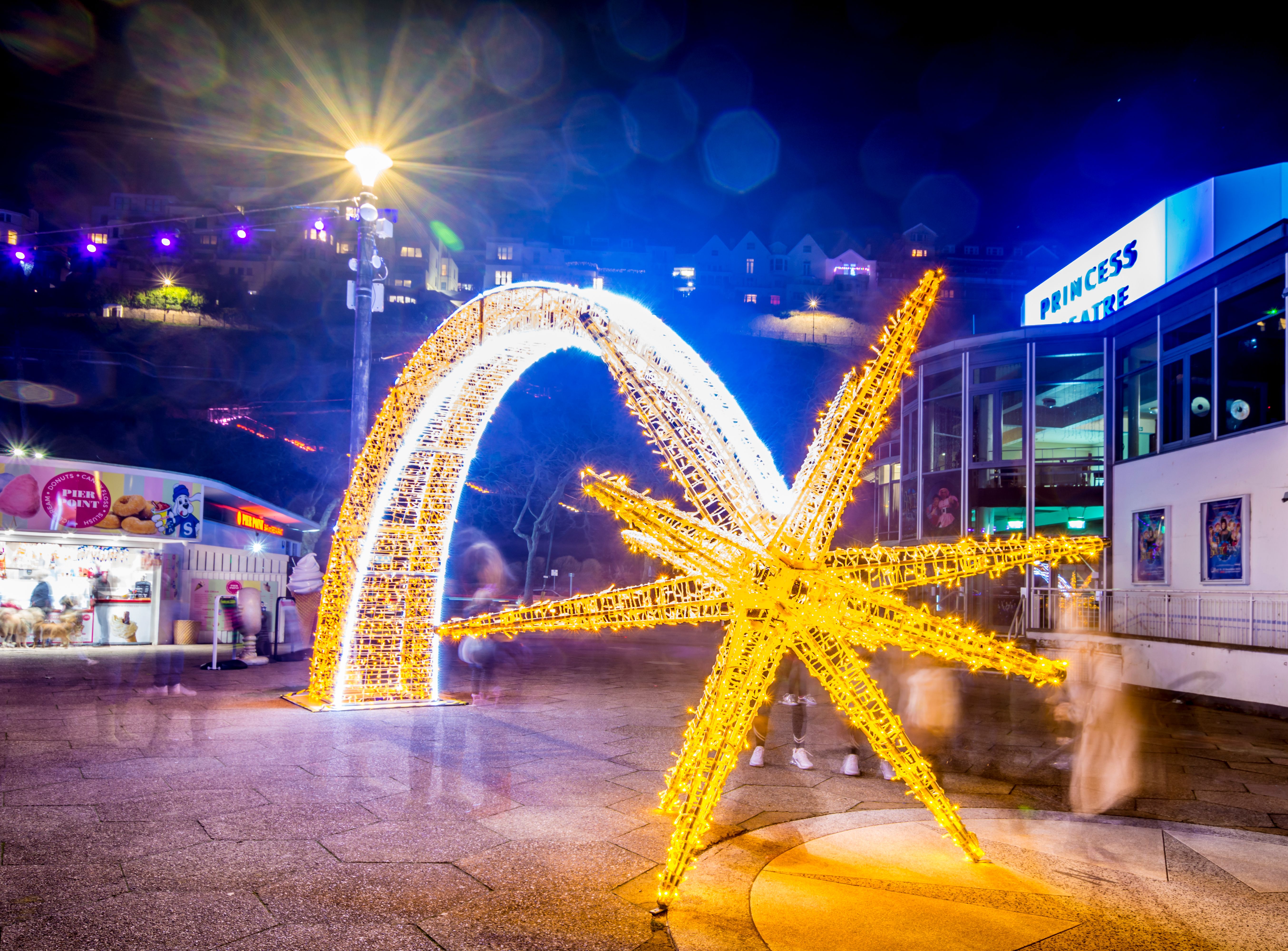 Illuminated golden starfish and arch light display outside the Princess Theatre at night