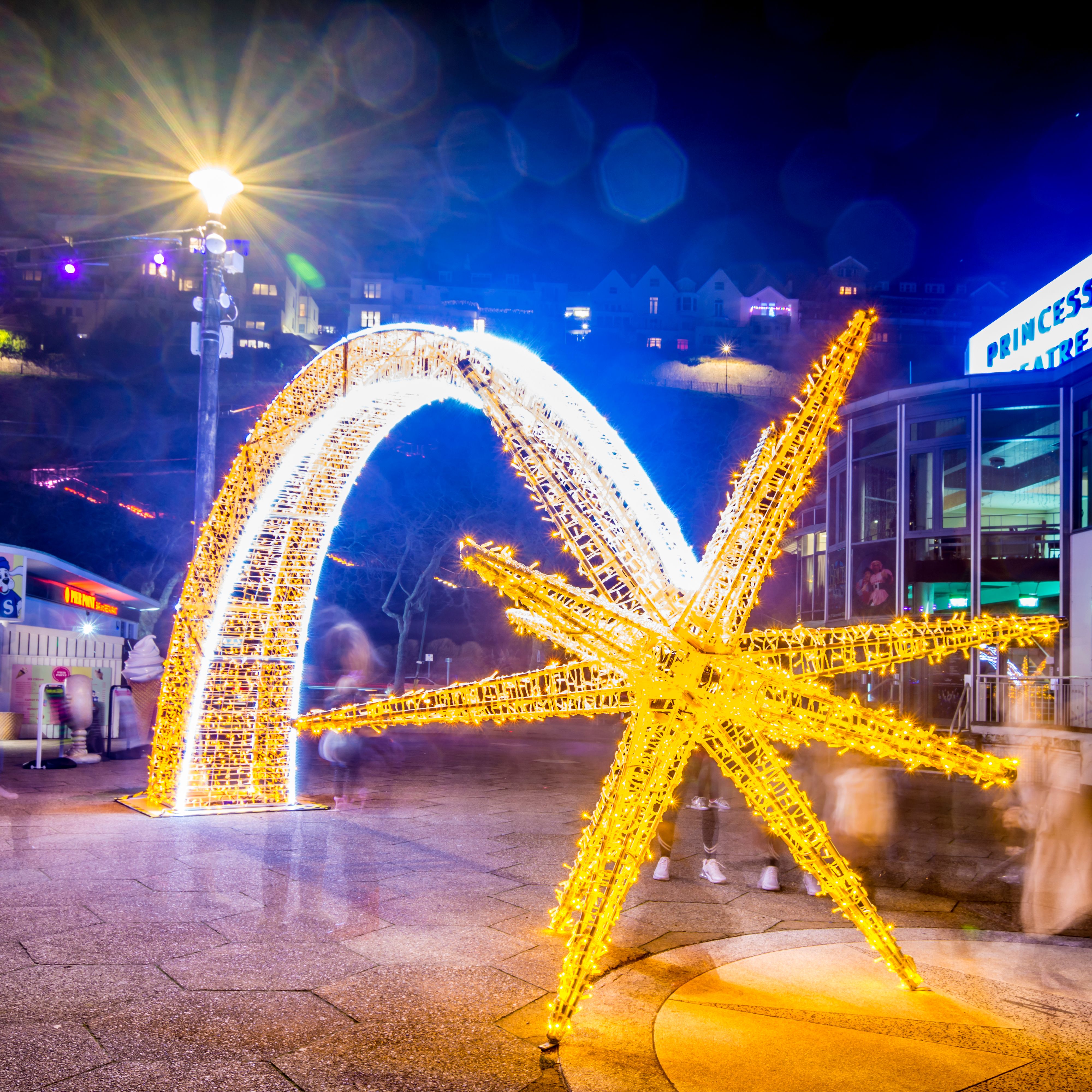 Illuminated golden starfish and arch light display outside the Princess Theatre at night