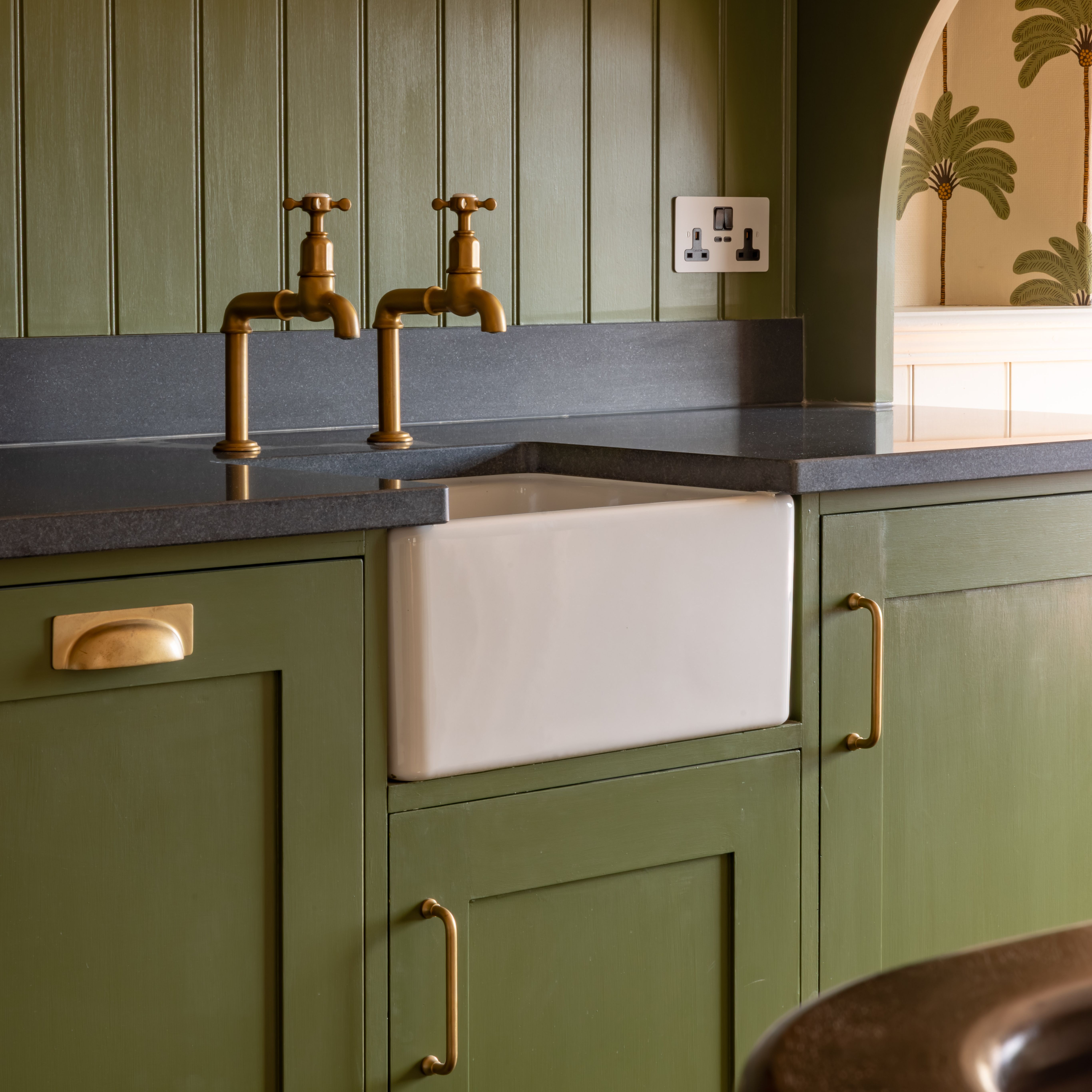 Victorian-style kitchen with green cabinets and a white ceramic sink