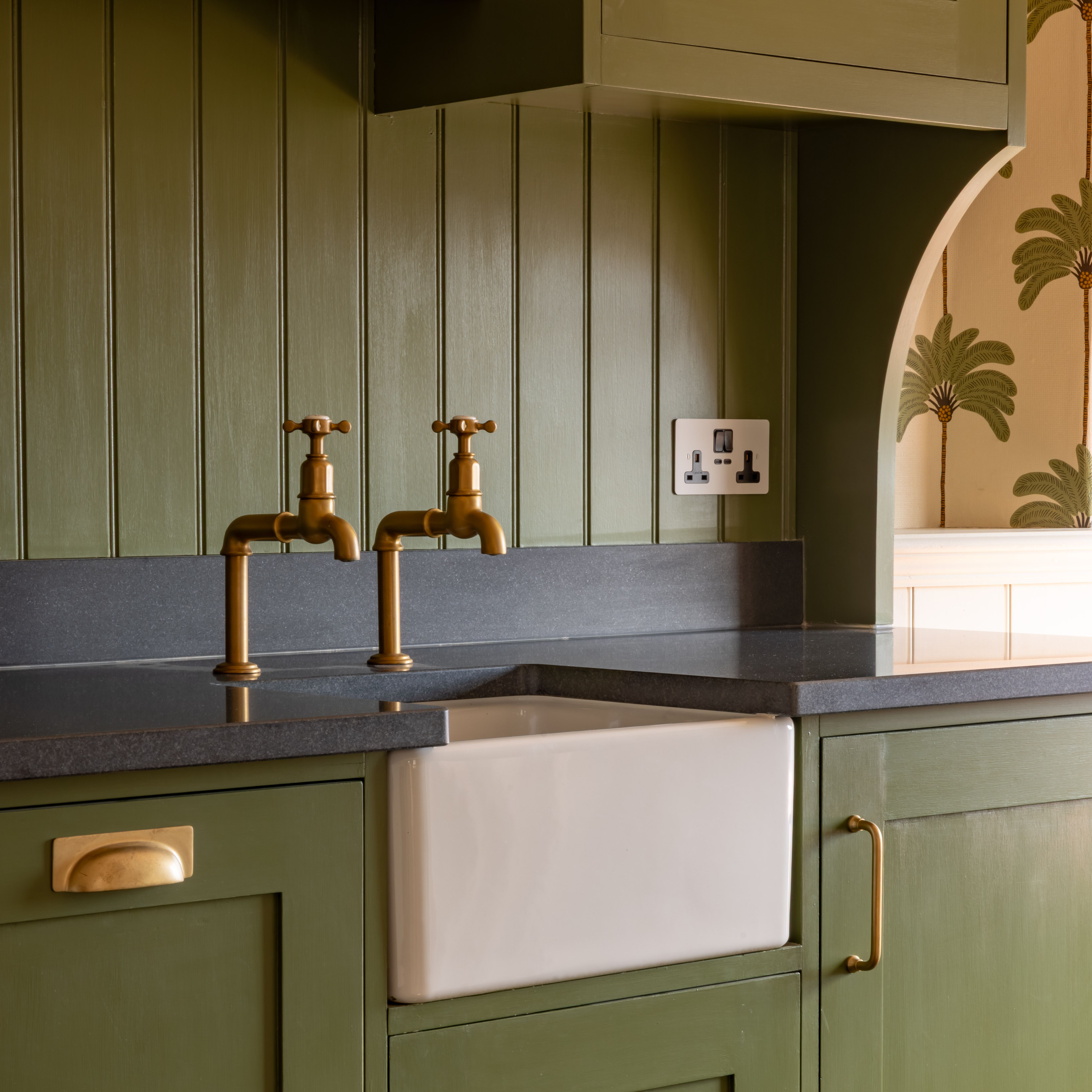 Victorian-style kitchen with green cabinets and a white ceramic sink