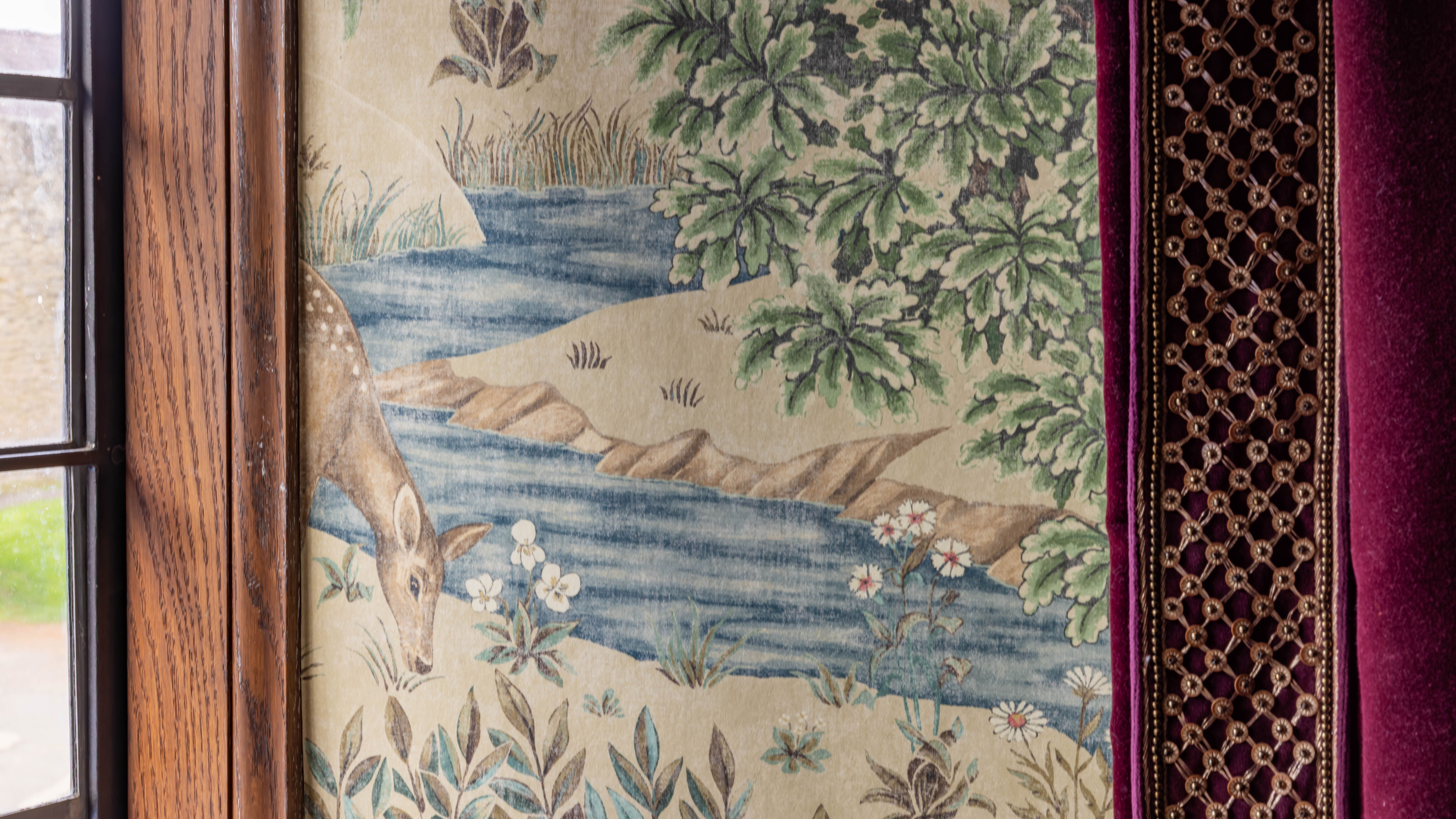 Historic wallpaper featuring a painted deer by a stream with flowers and foliage