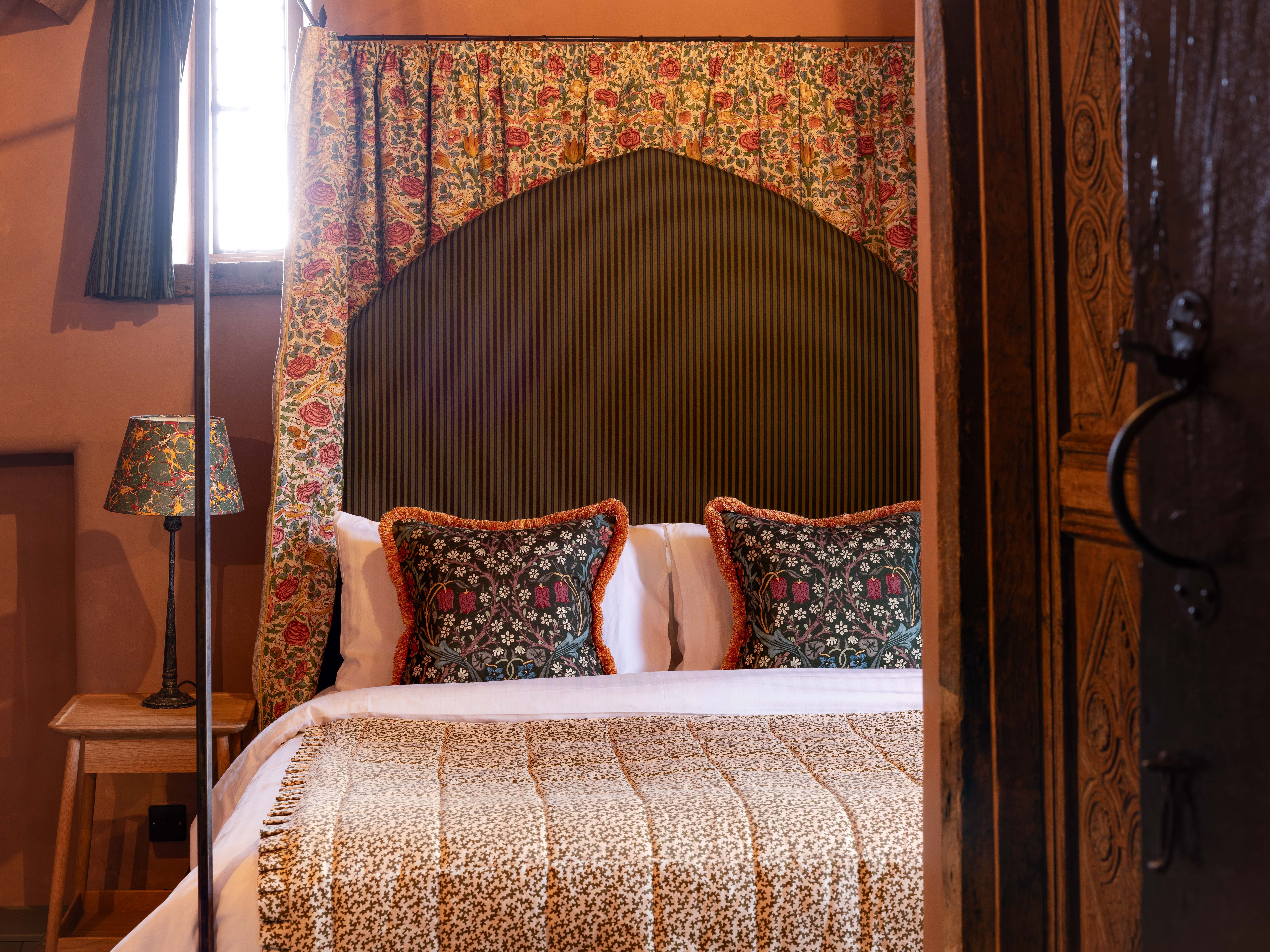 Cozy bed with floral pillows and draped headboard in a warmly lit bedroom