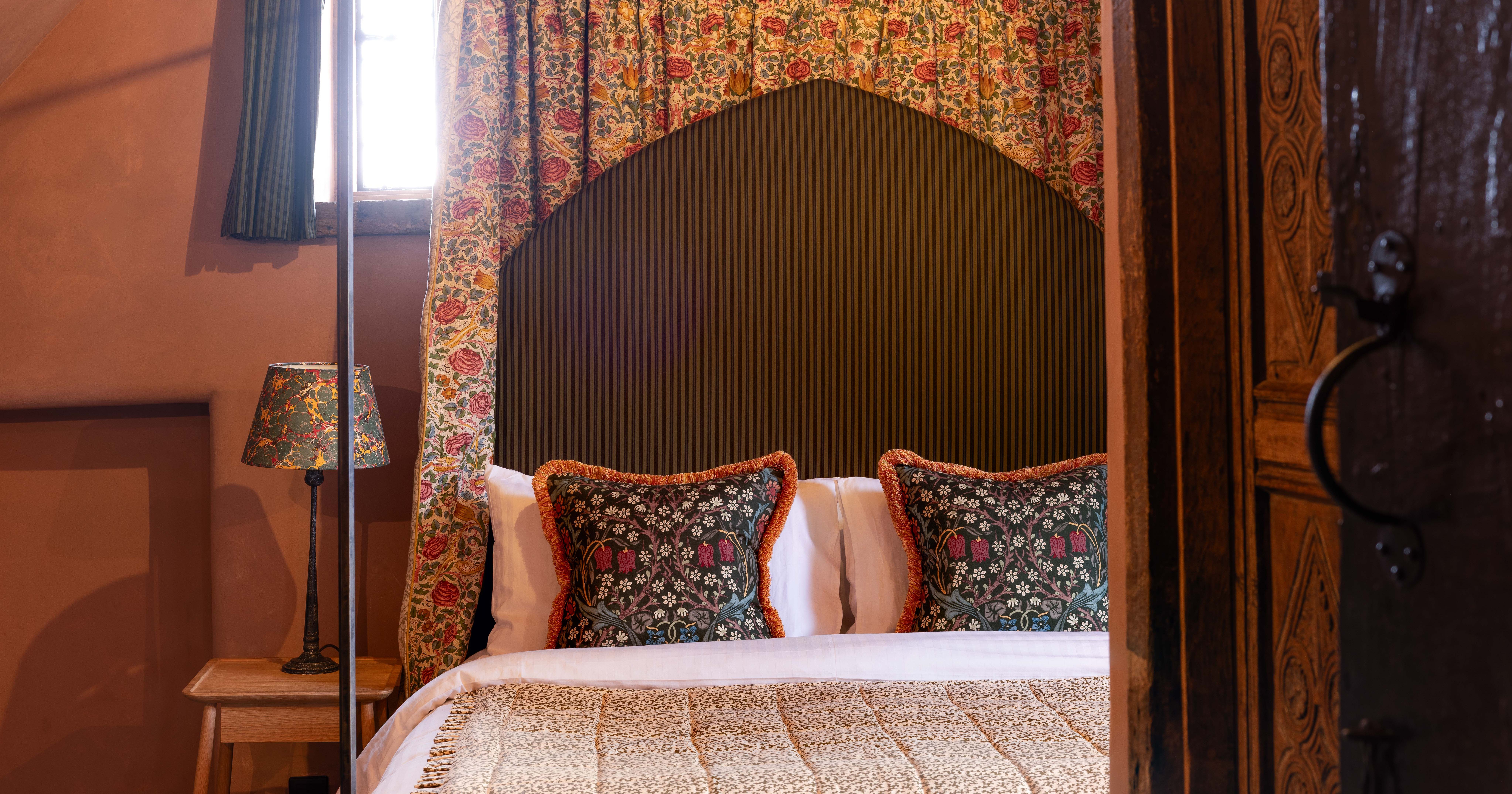 Cozy bed with floral pillows and draped headboard in a warmly lit bedroom