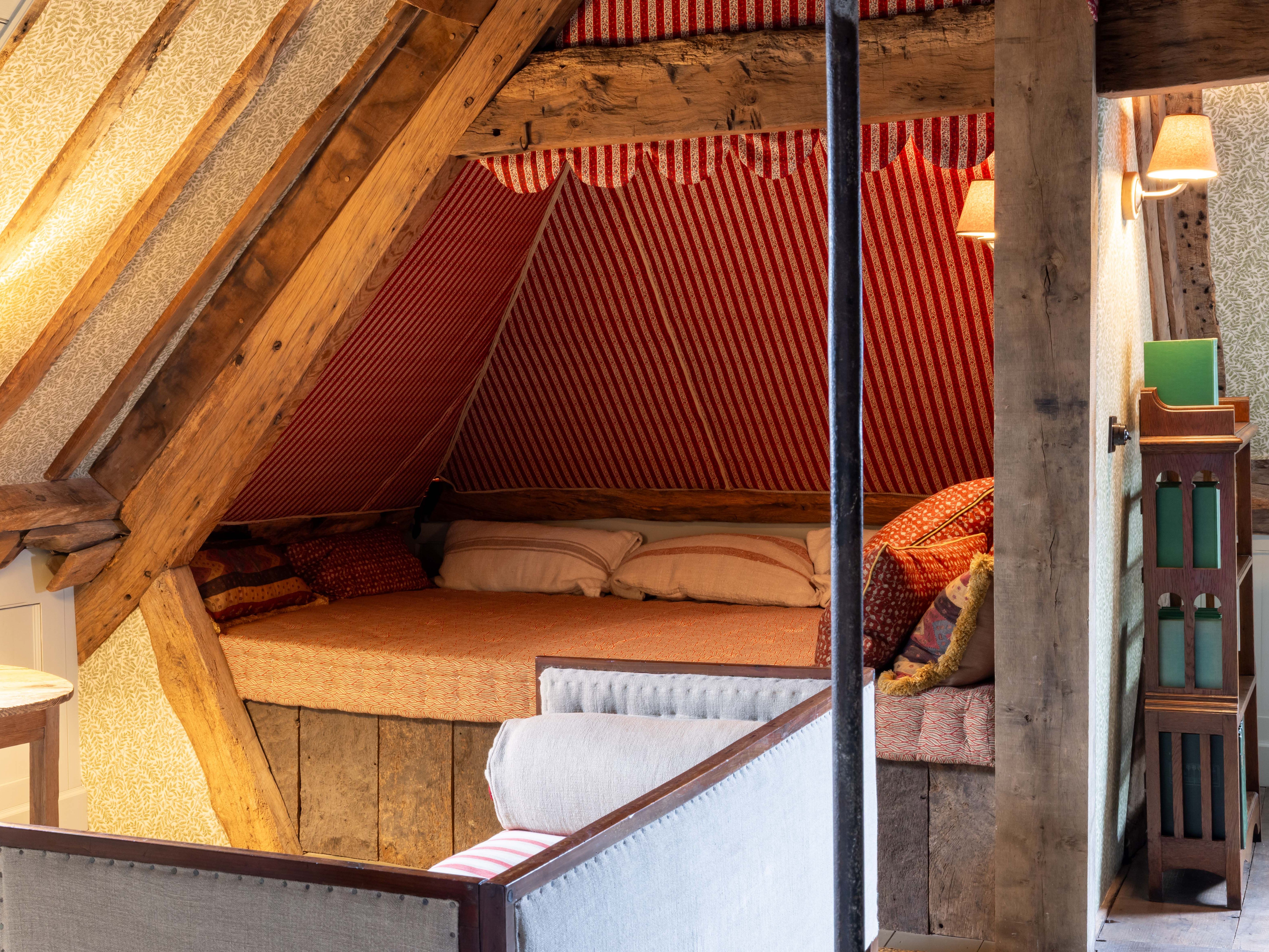 Cozy attic day bed with wooden beams and patterned textiles