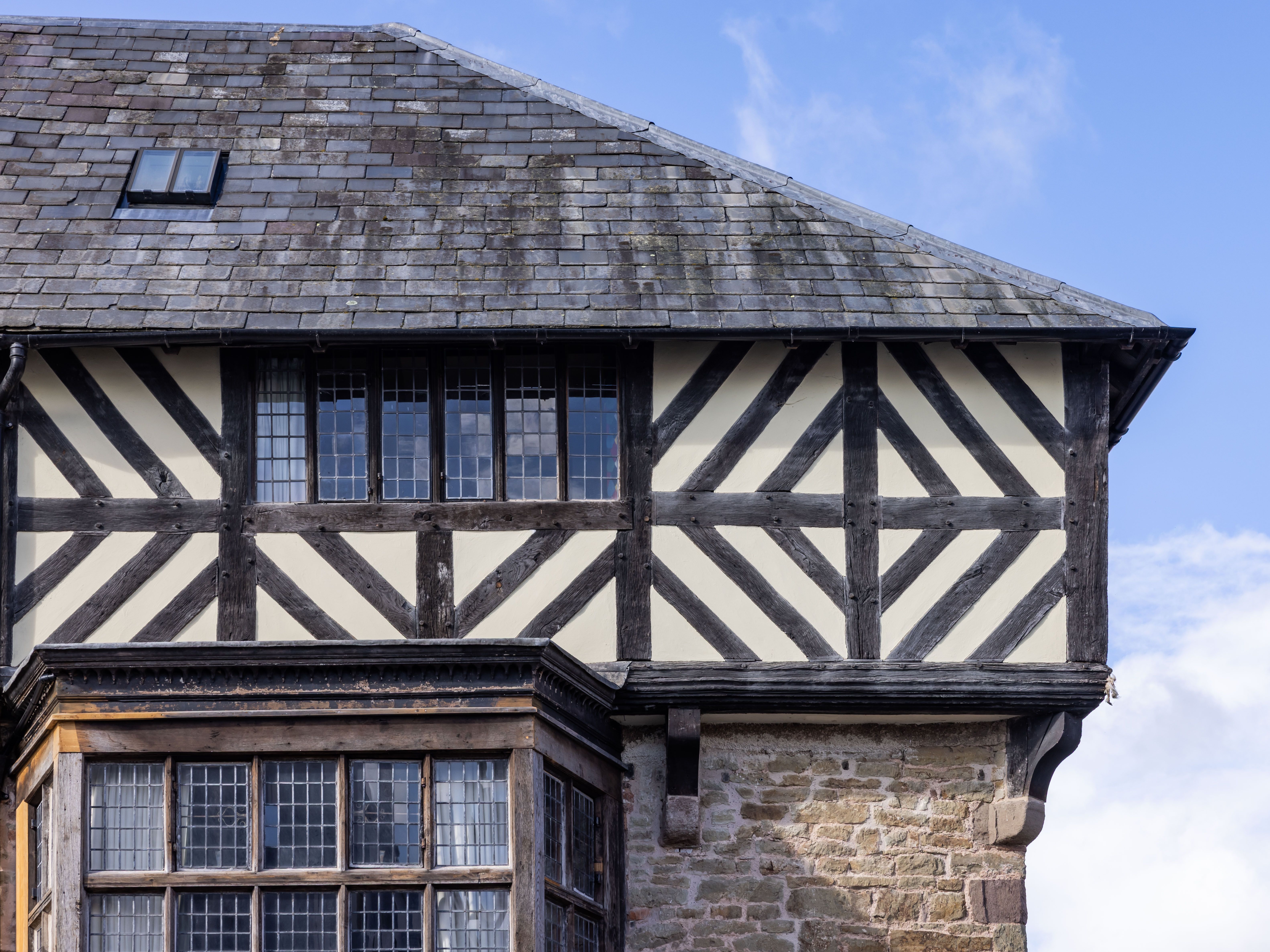 Exterior detail of a historic half-timbered building with leaded windows and slate roof