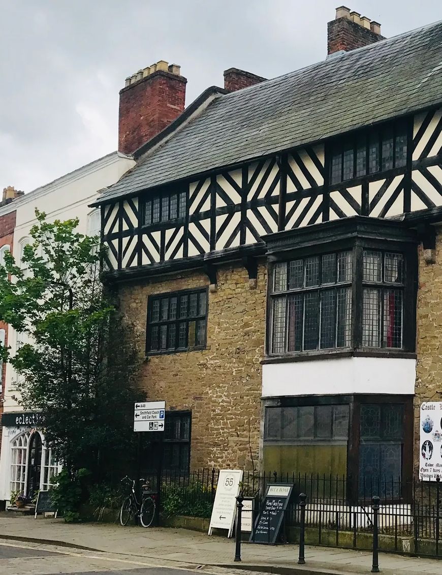 Historic Tudor-style building with black and white timber frame upper floor and stone lower floor on a street corner.