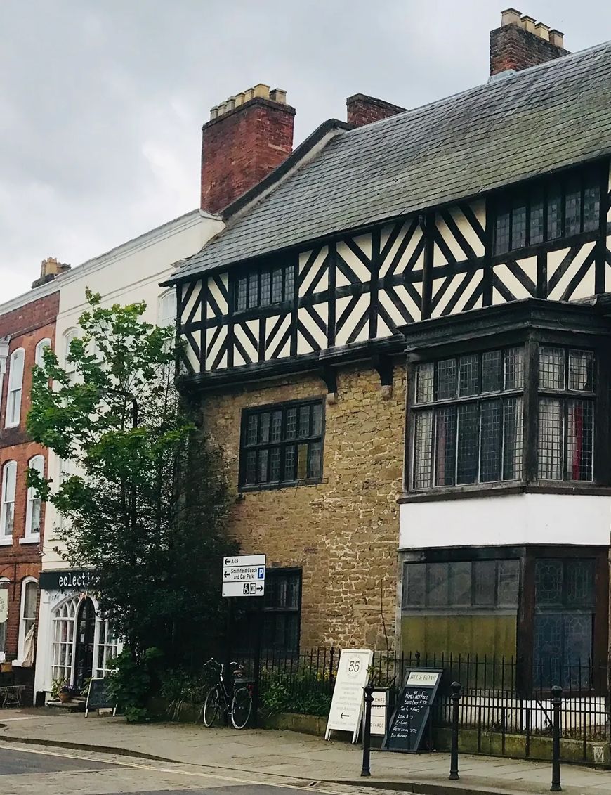 Historic Tudor-style building with black and white timber frame upper floor and stone lower floor on a street corner.