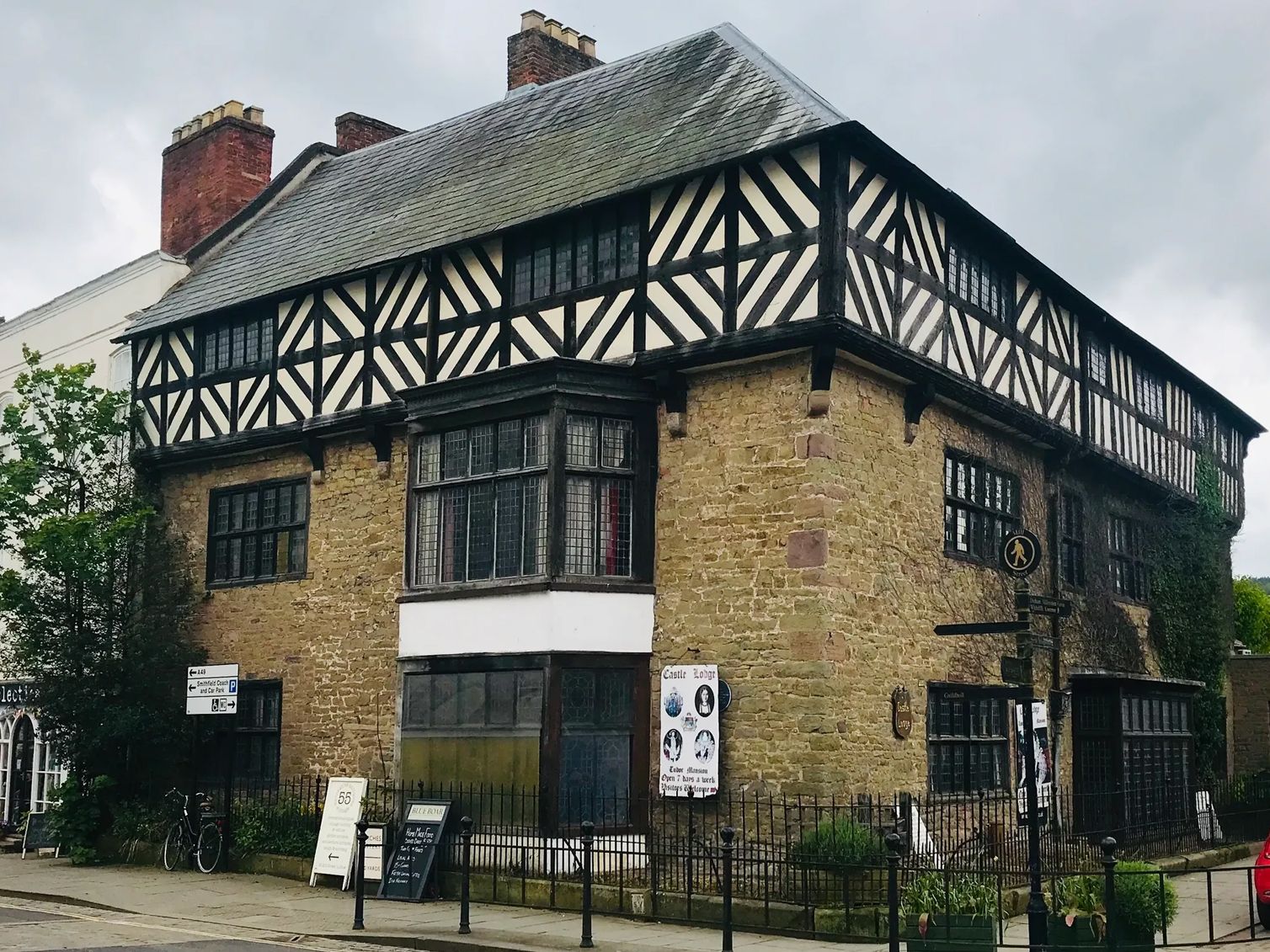 Historic Tudor-style building with black and white timber frame upper floor and stone lower floor on a street corner.