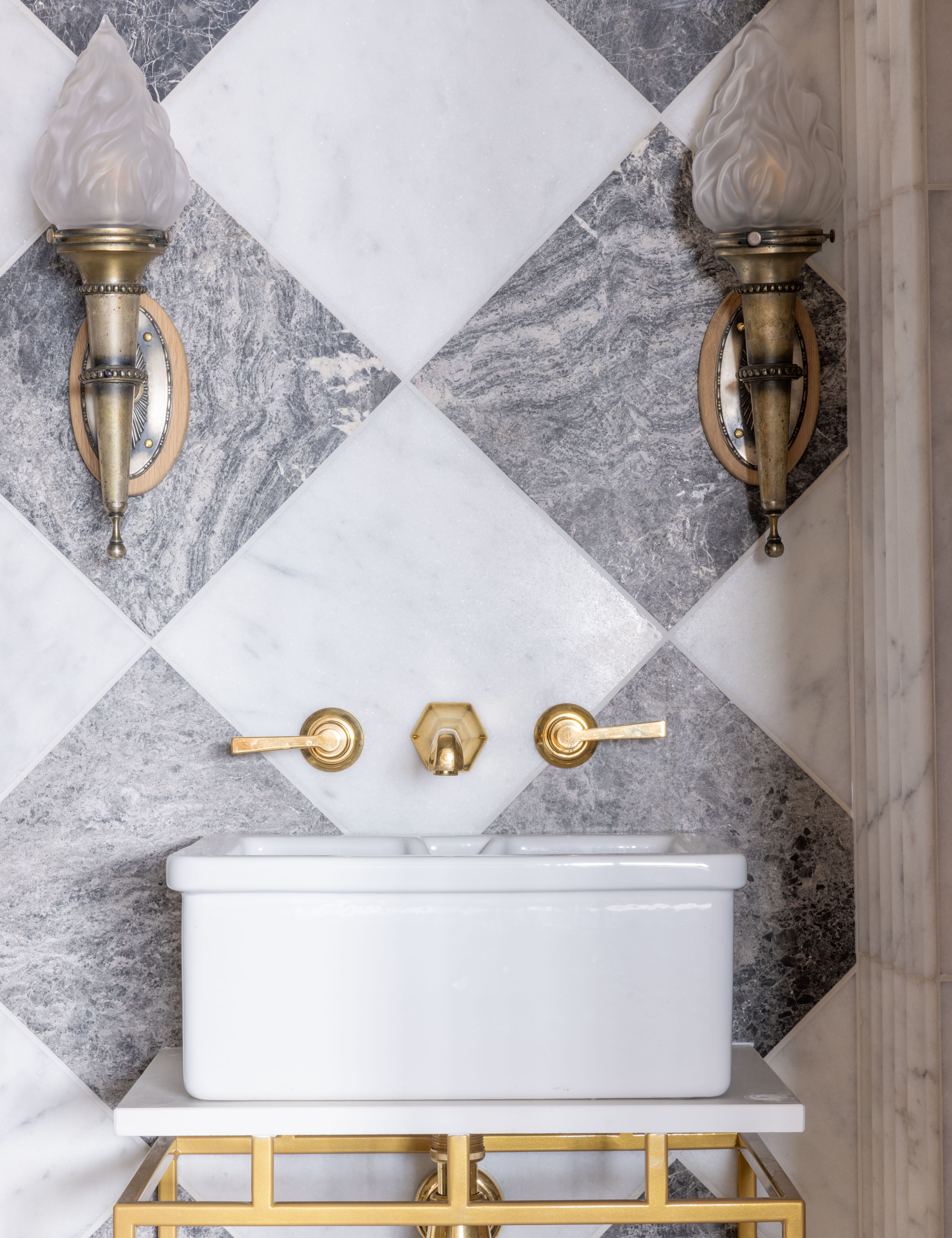 Elegant bathroom sink with gold fixtures and geometric gray and white tiled wall