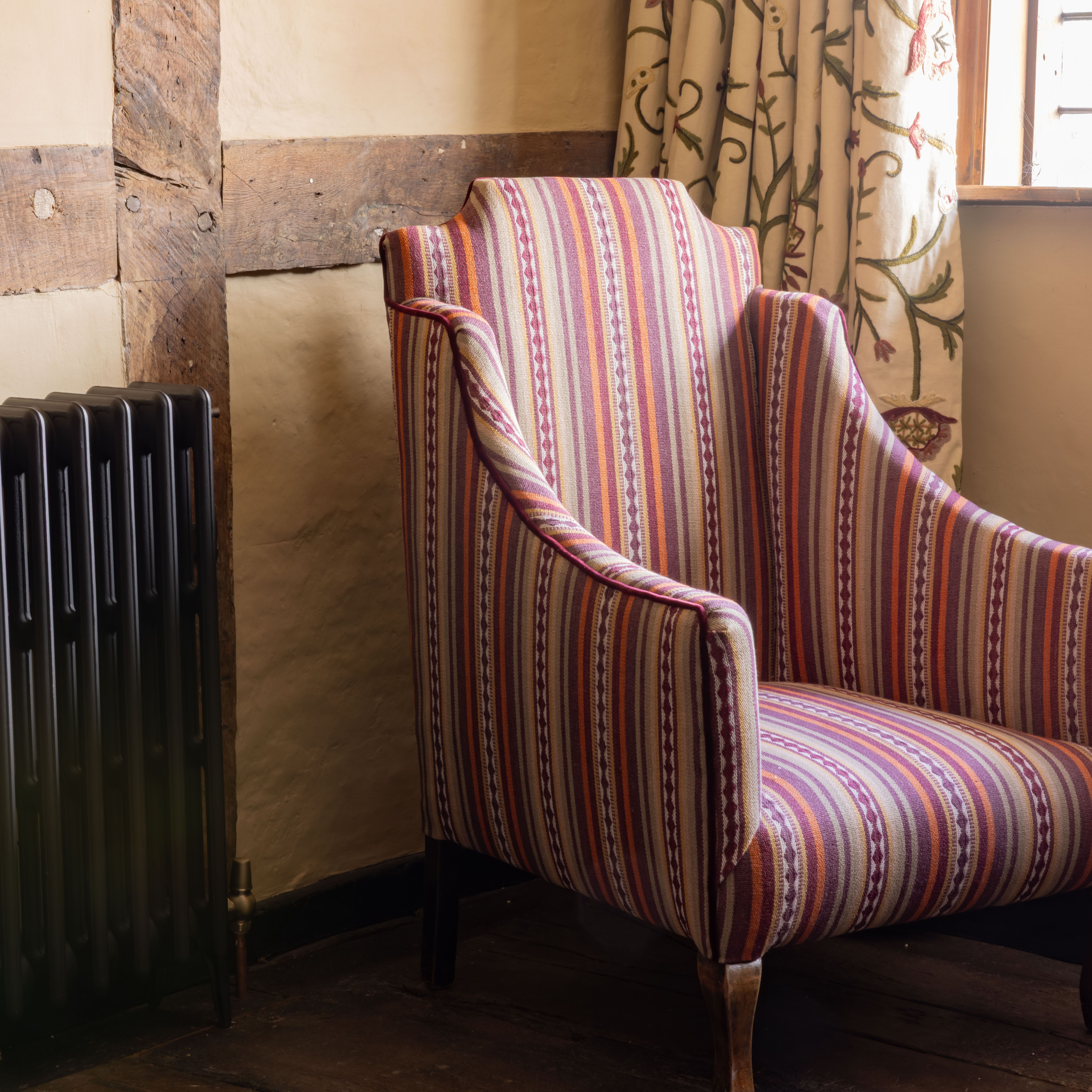 Striped vintage armchair in a rustic room beside a window