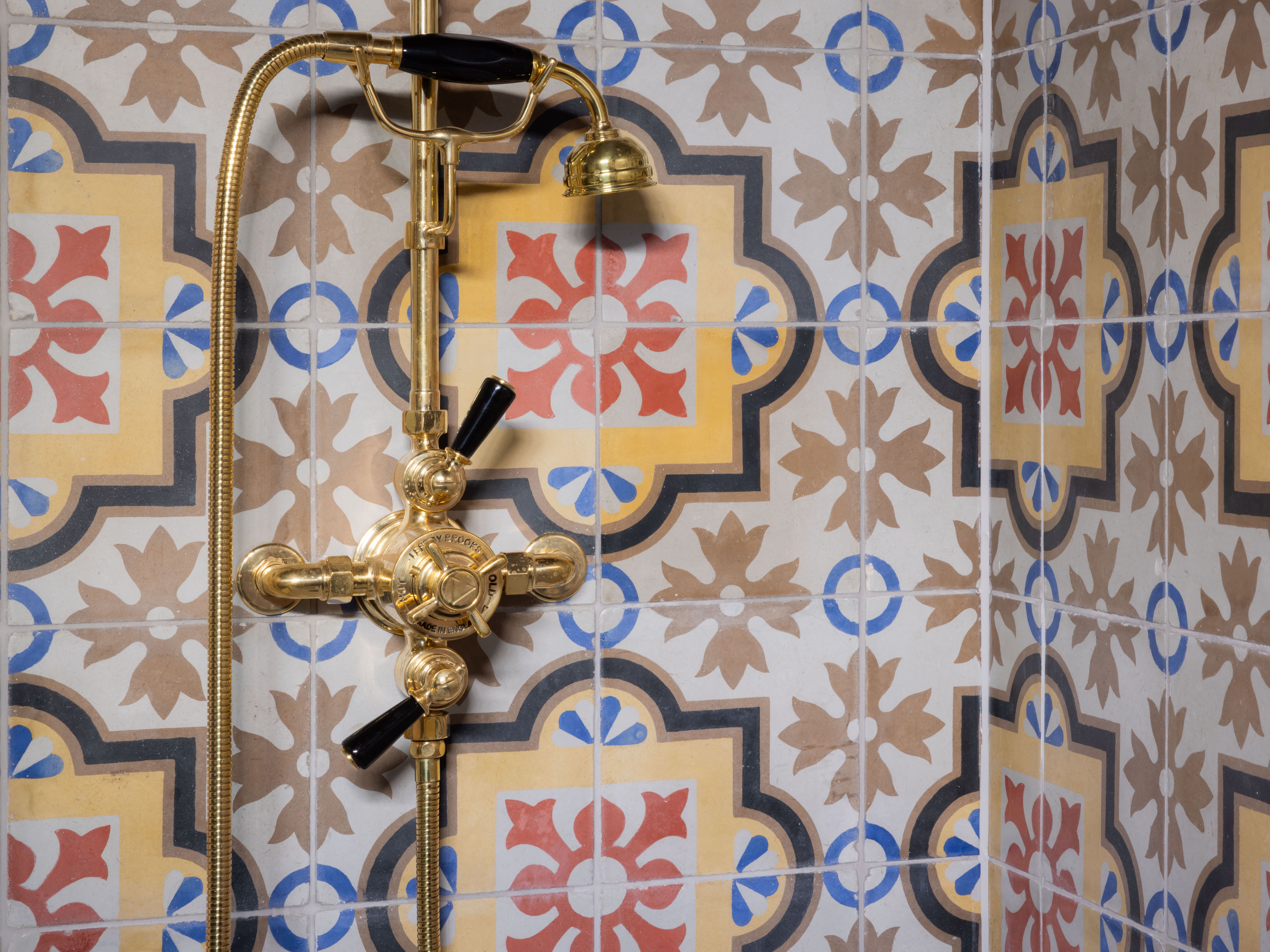 Ornate brass shower fixture against colorful patterned tiles