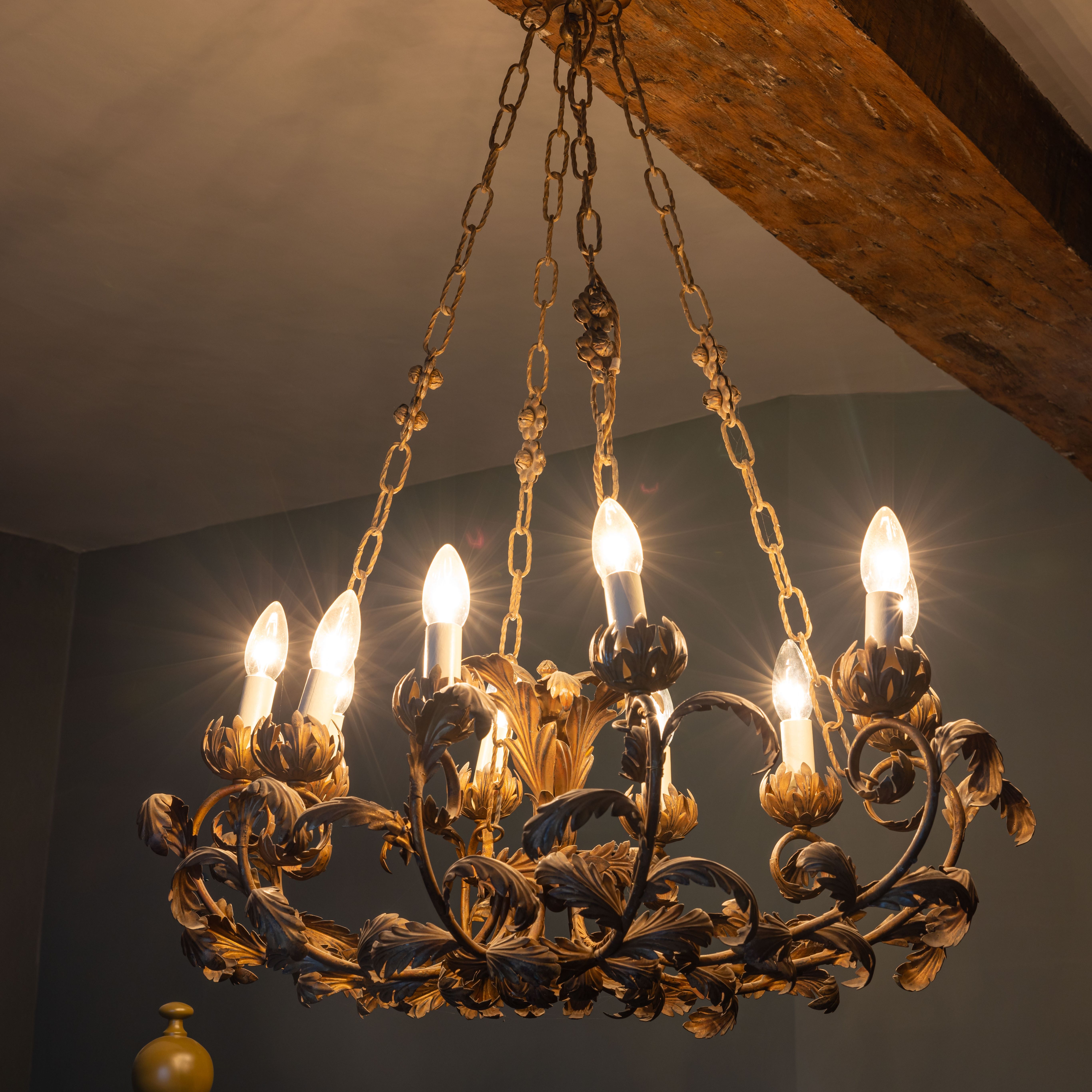 Ornate chandelier with lit candle-shaped bulbs hanging from a ceiling beam