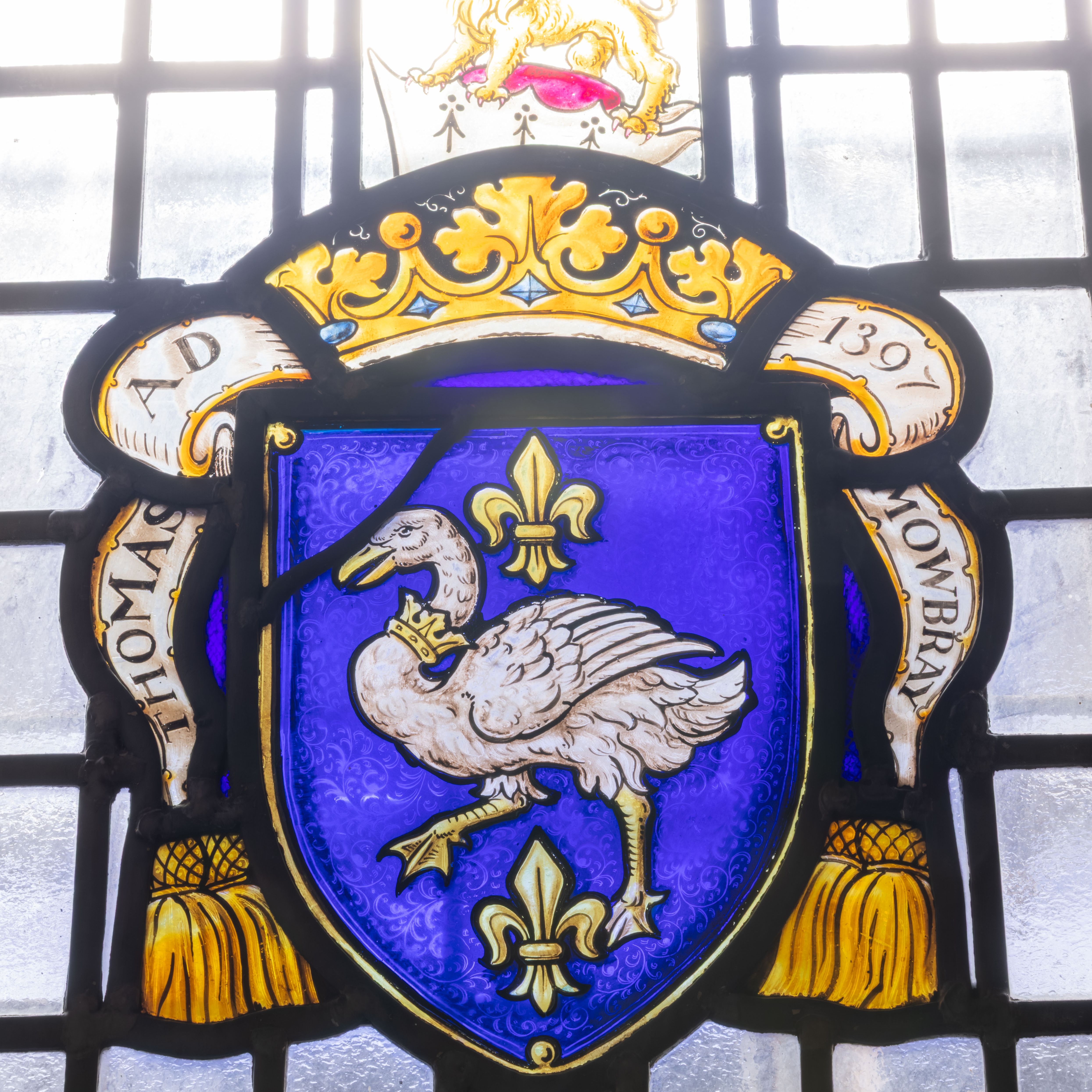 Stained glass window with a heraldic crest featuring a crowned white swan and fleur-de-lis