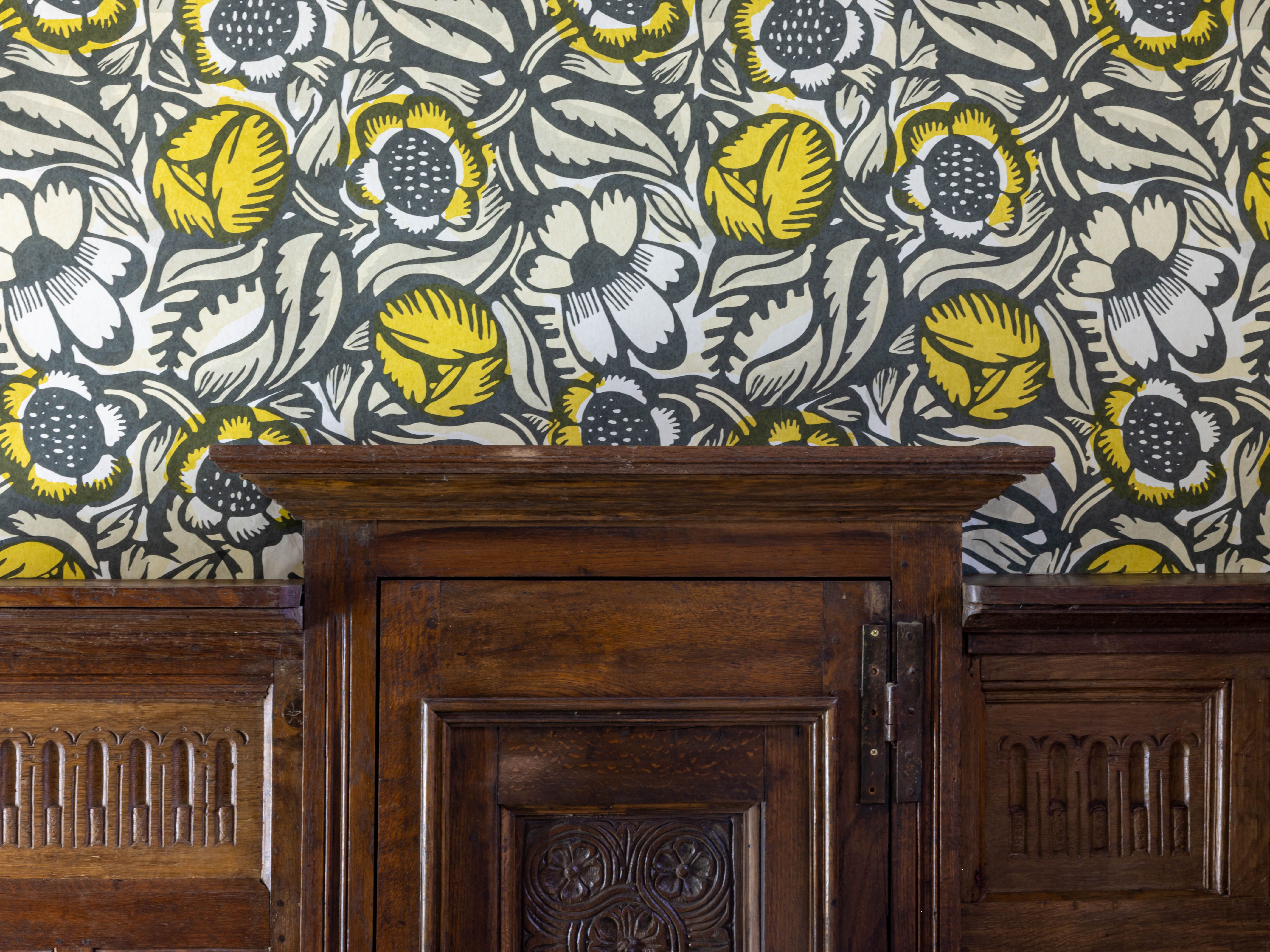 Wooden paneling beneath floral patterned wallpaper with yellow and white flowers