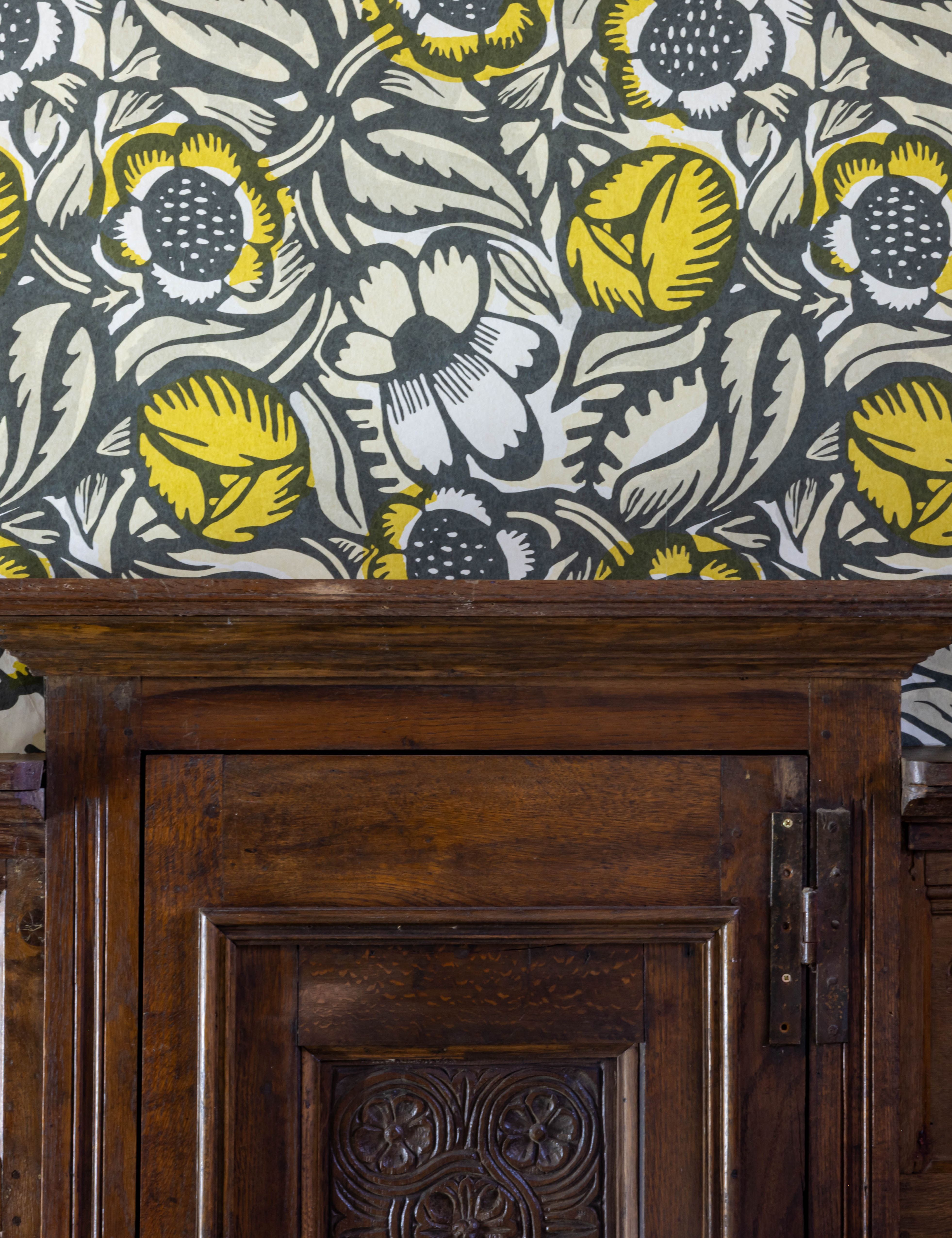 Wooden paneling beneath floral patterned wallpaper with yellow and white flowers