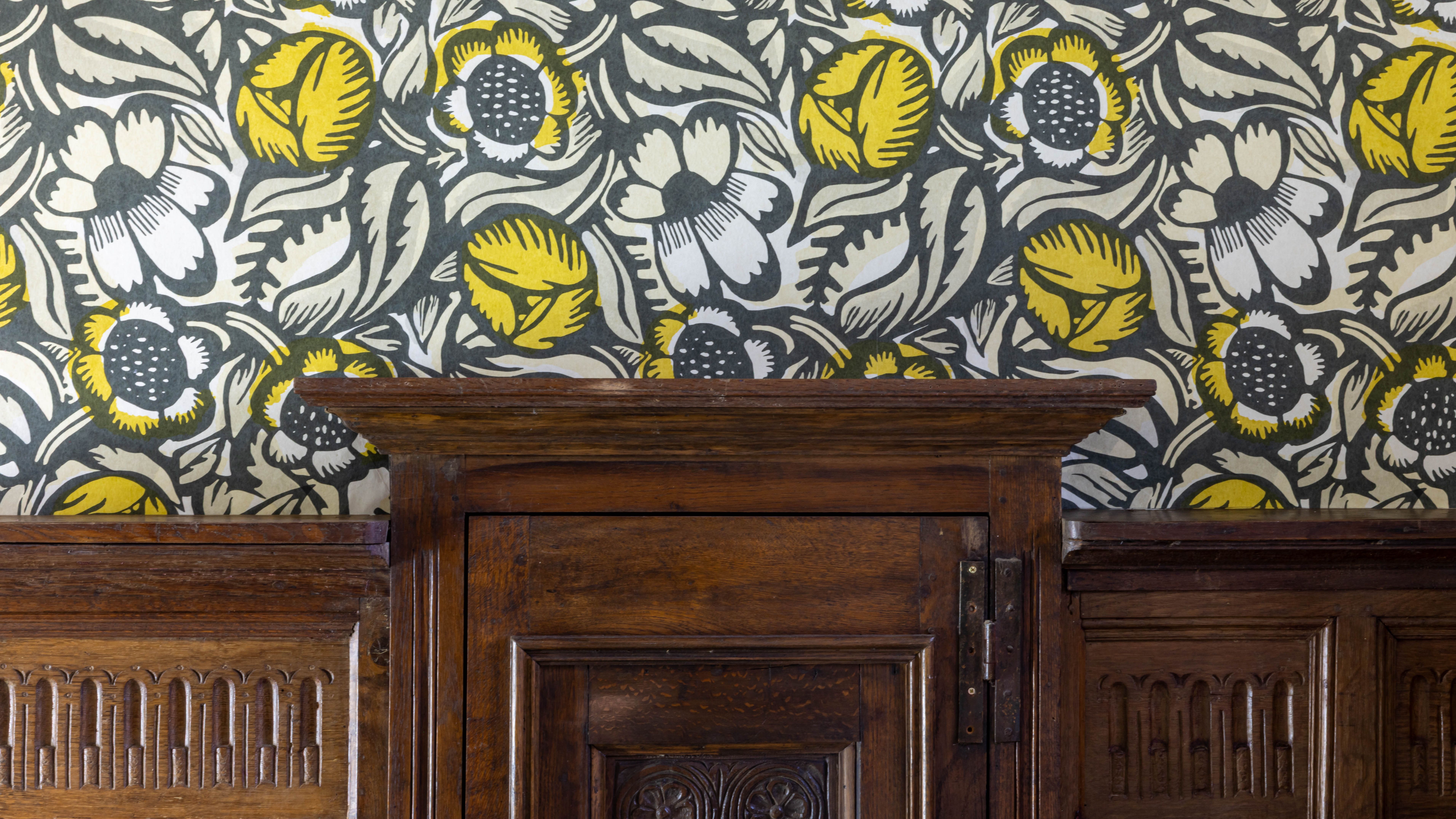 Wooden paneling beneath floral patterned wallpaper with yellow and white flowers