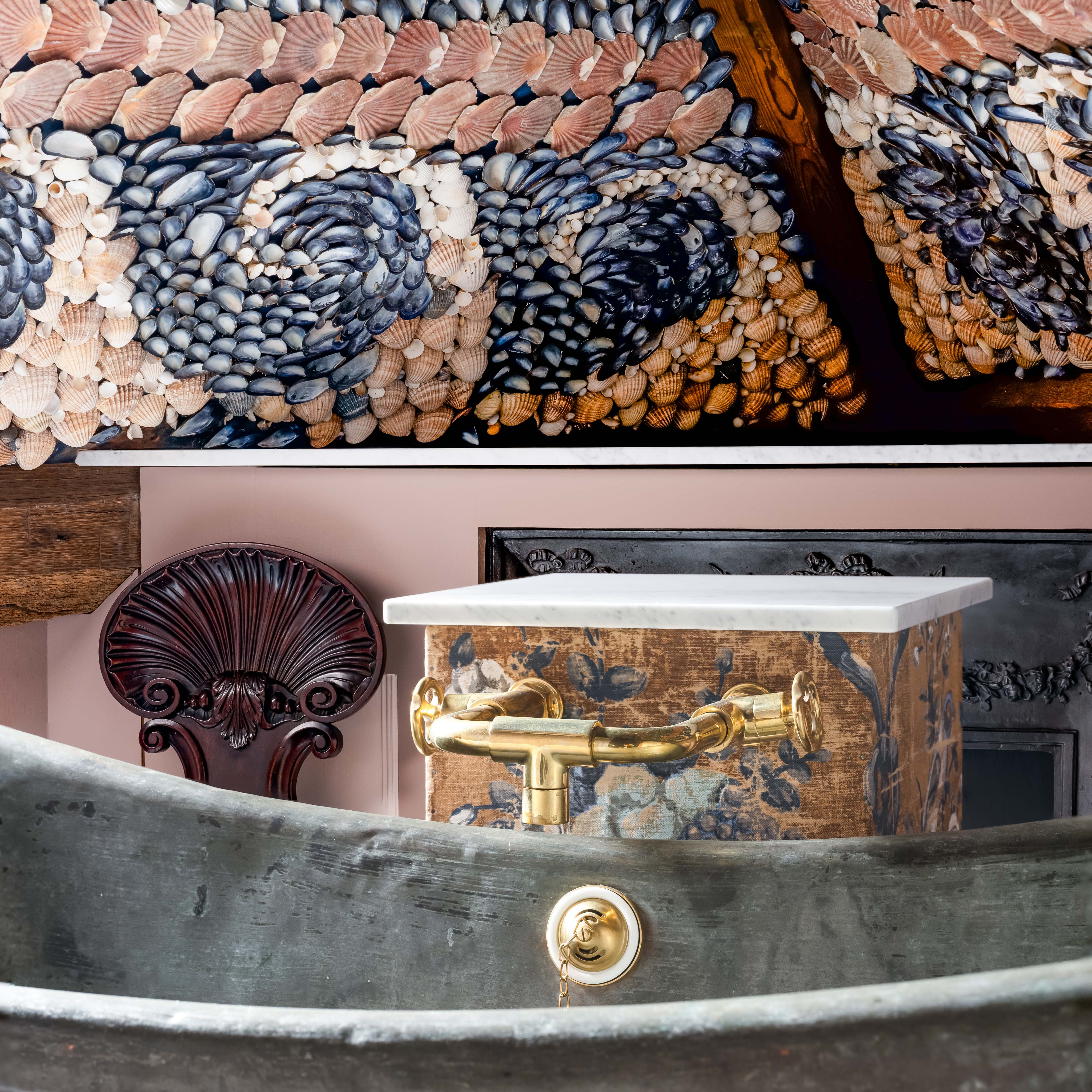 Luxurious bathtub with ornate brass faucet and shell mosaic ceiling