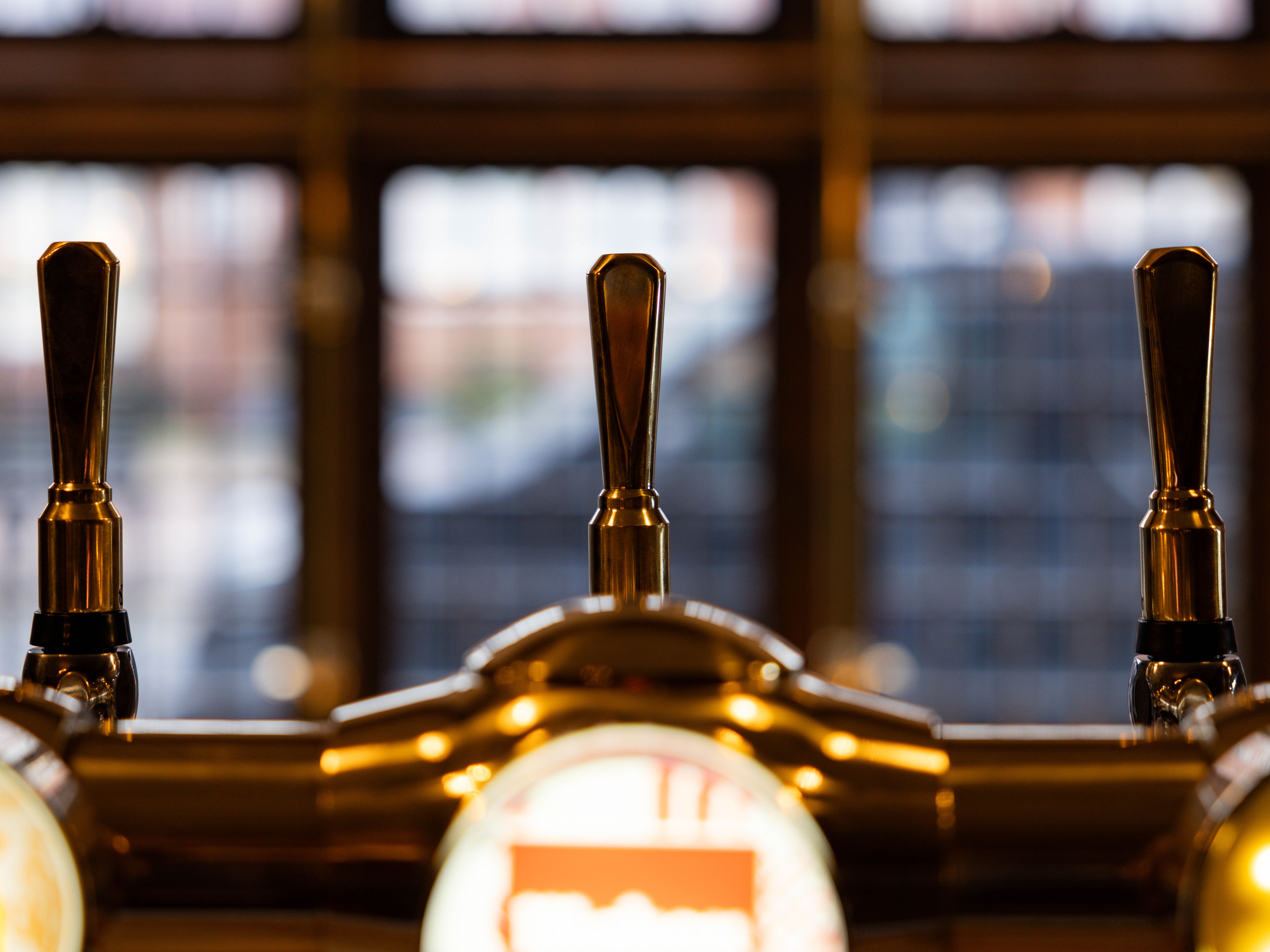 Close-up of bar taps in front of a blurred window background