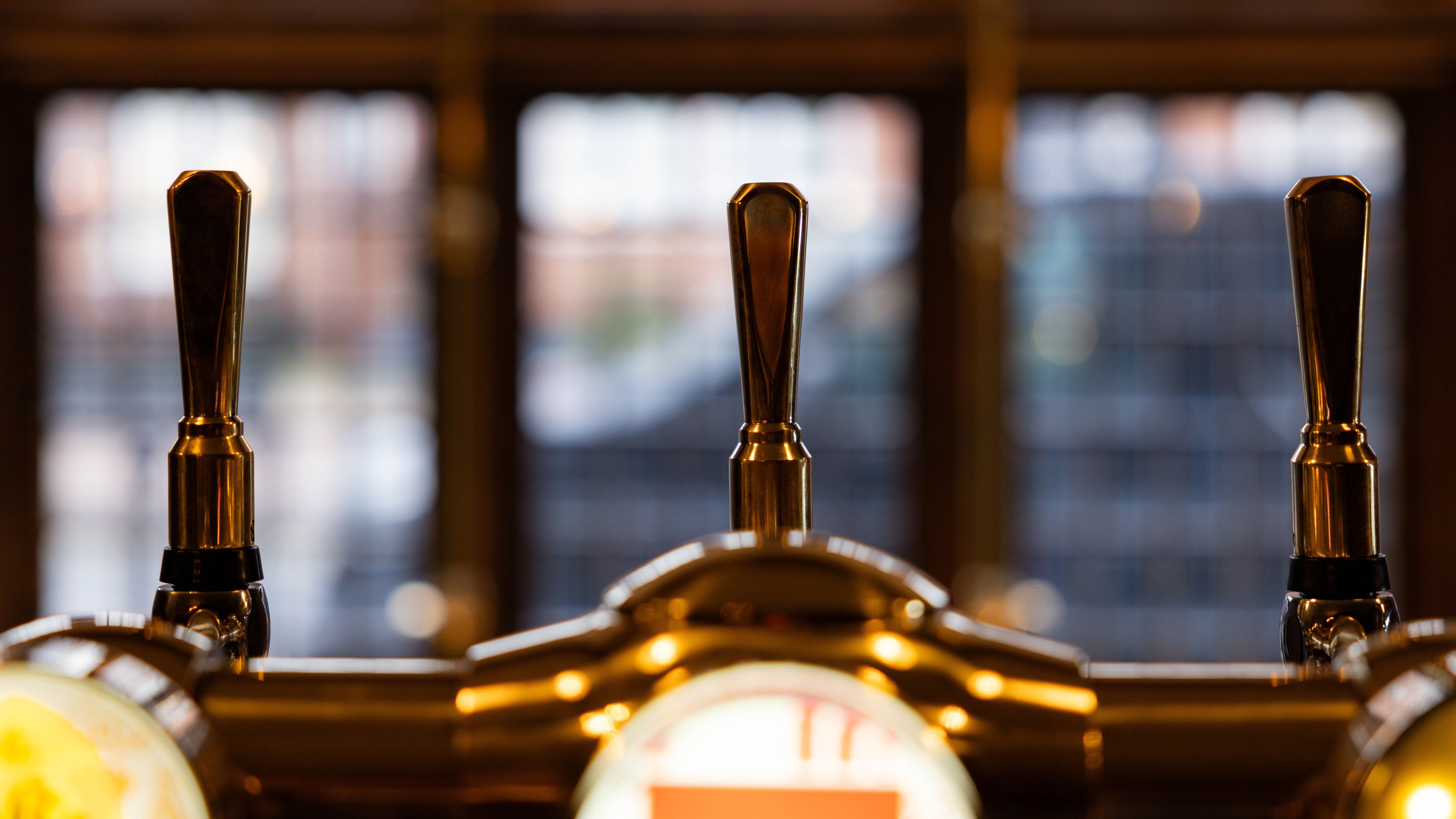 Close-up of bar taps in front of a blurred window background