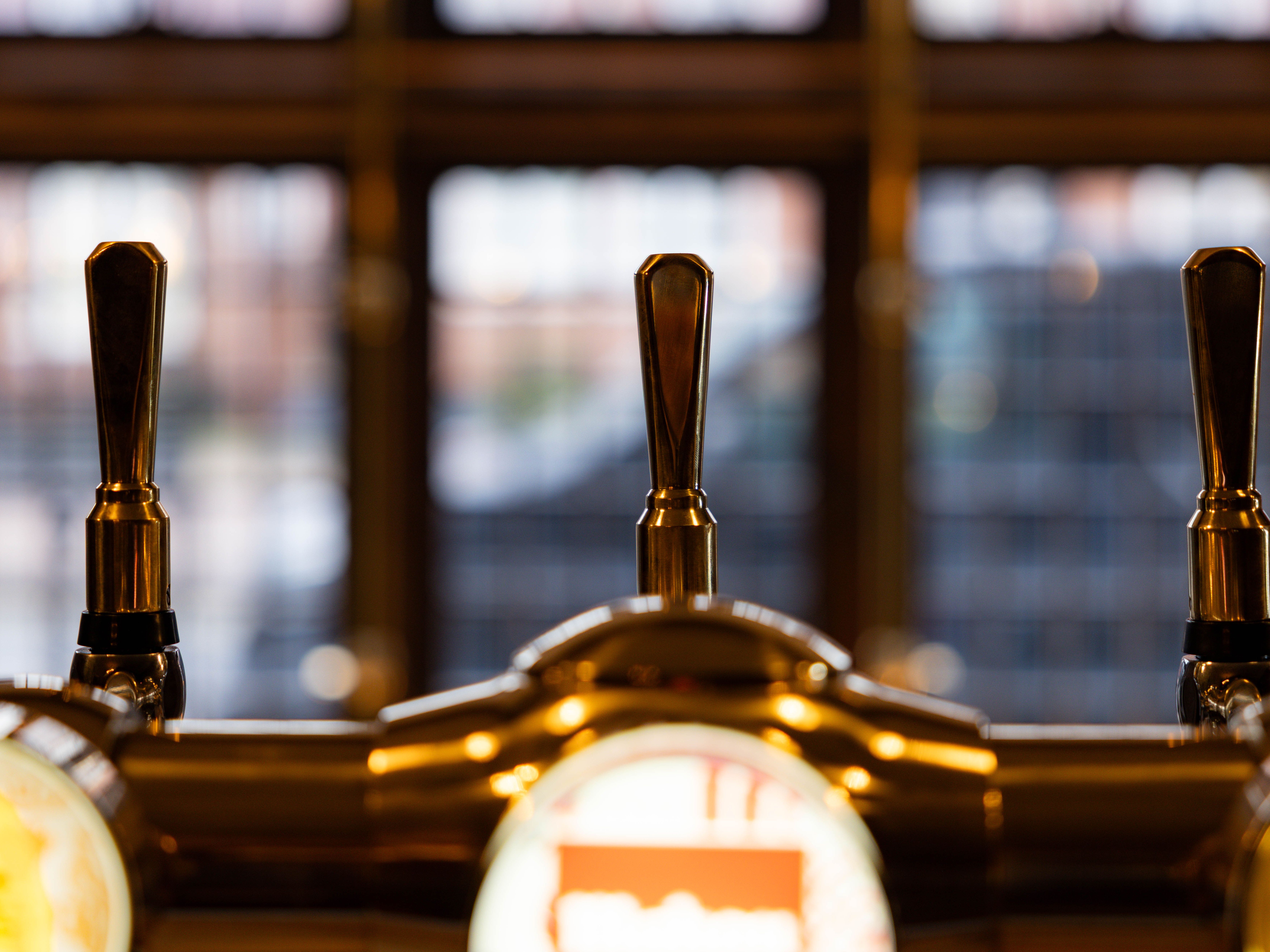 Close-up of bar taps in front of a blurred window background