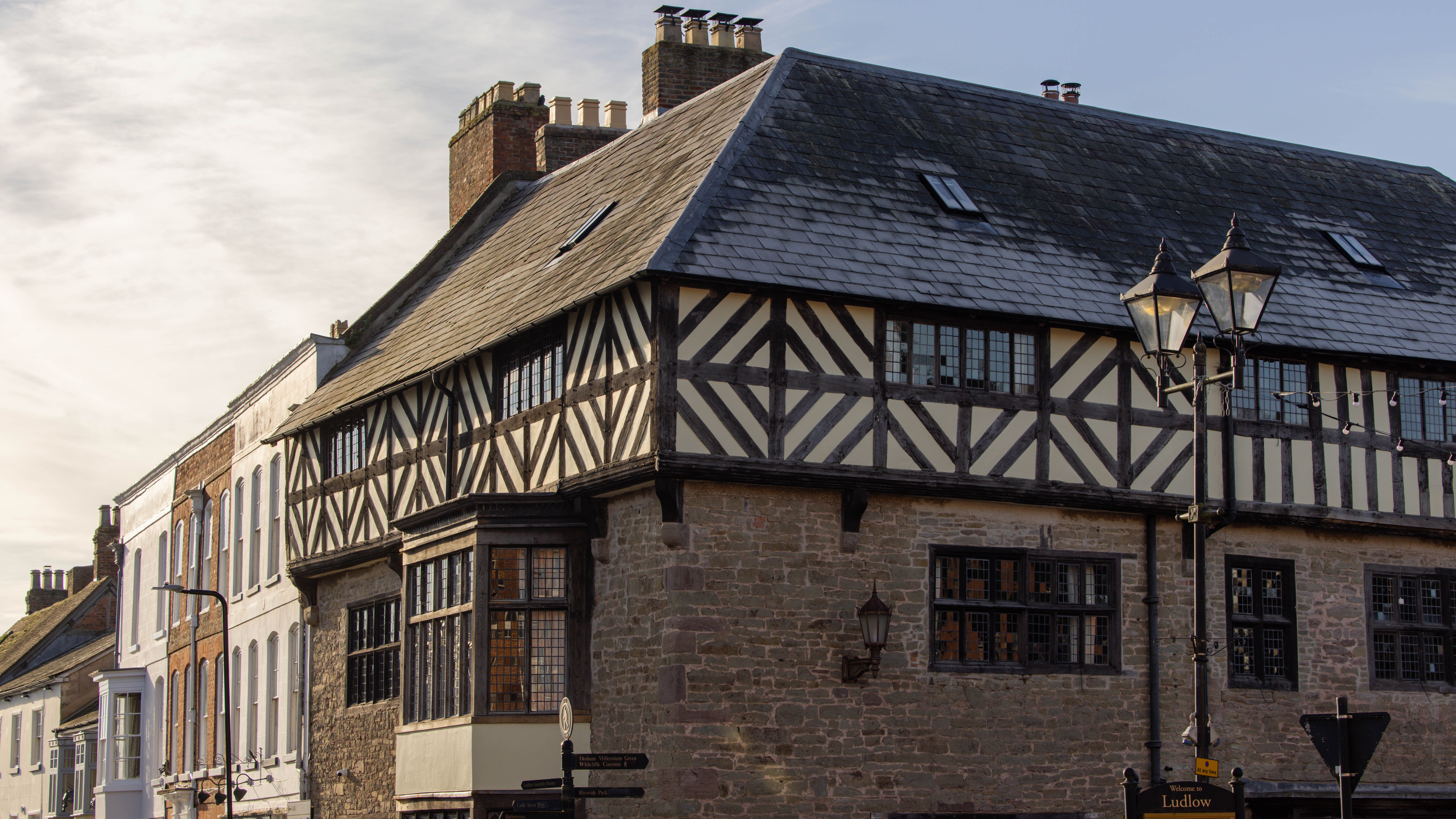 Historic timber-framed building on a street corner with antique street lamps.