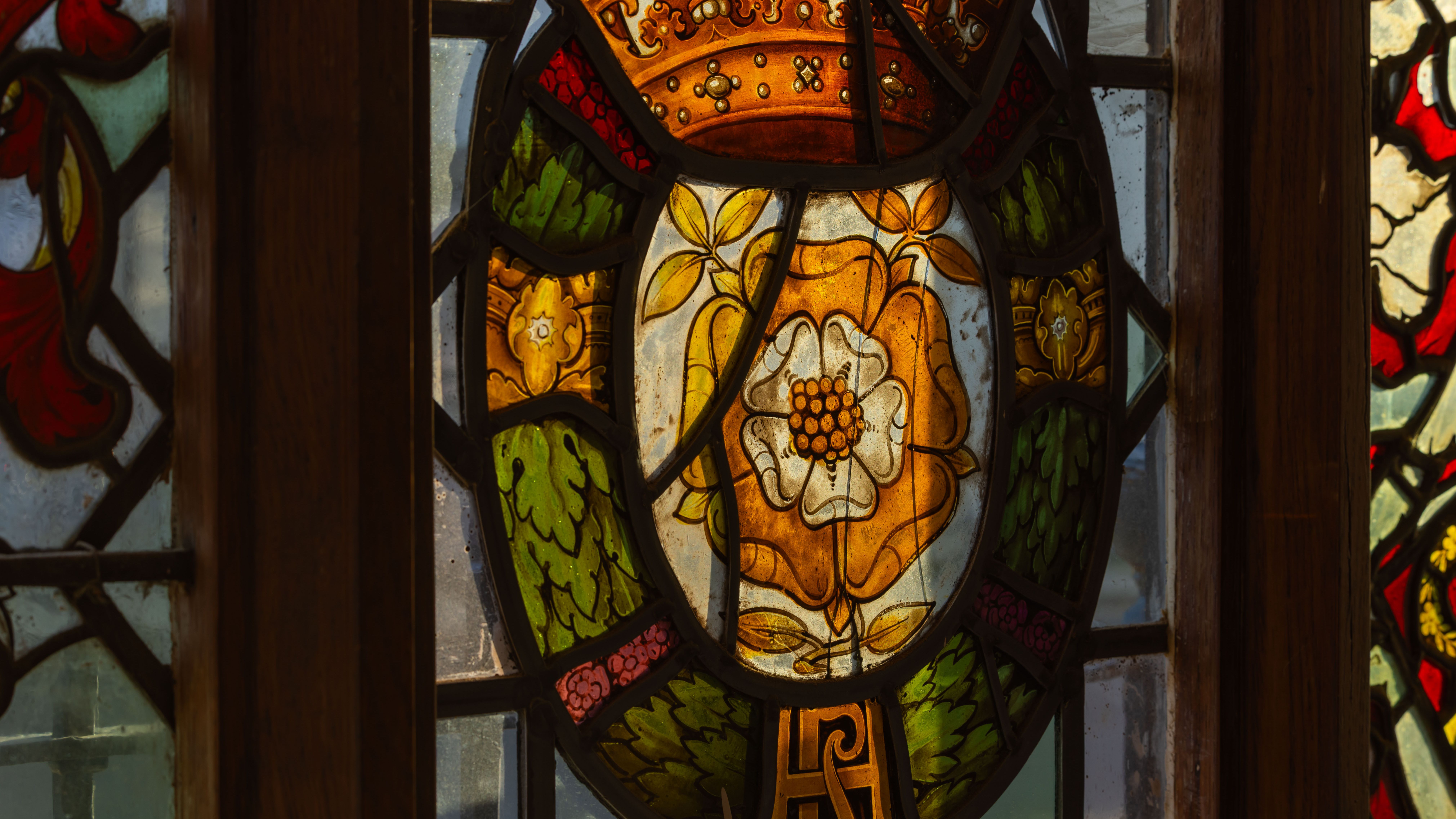 Stained glass window featuring the Tudor Rose design with vibrant colors and intricate details.