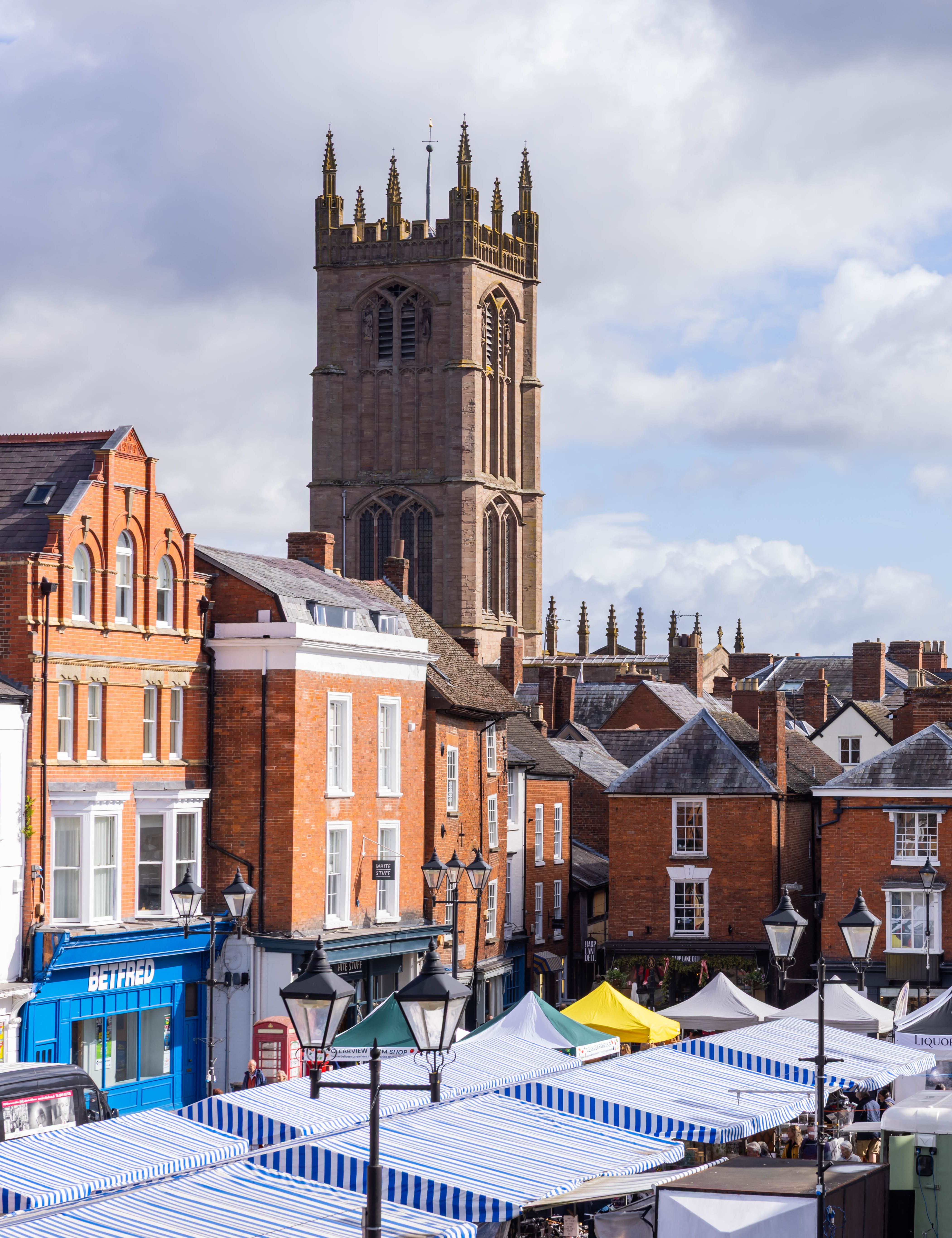 Town view of Ludlow with historic buildings, church tower, and market stalls.