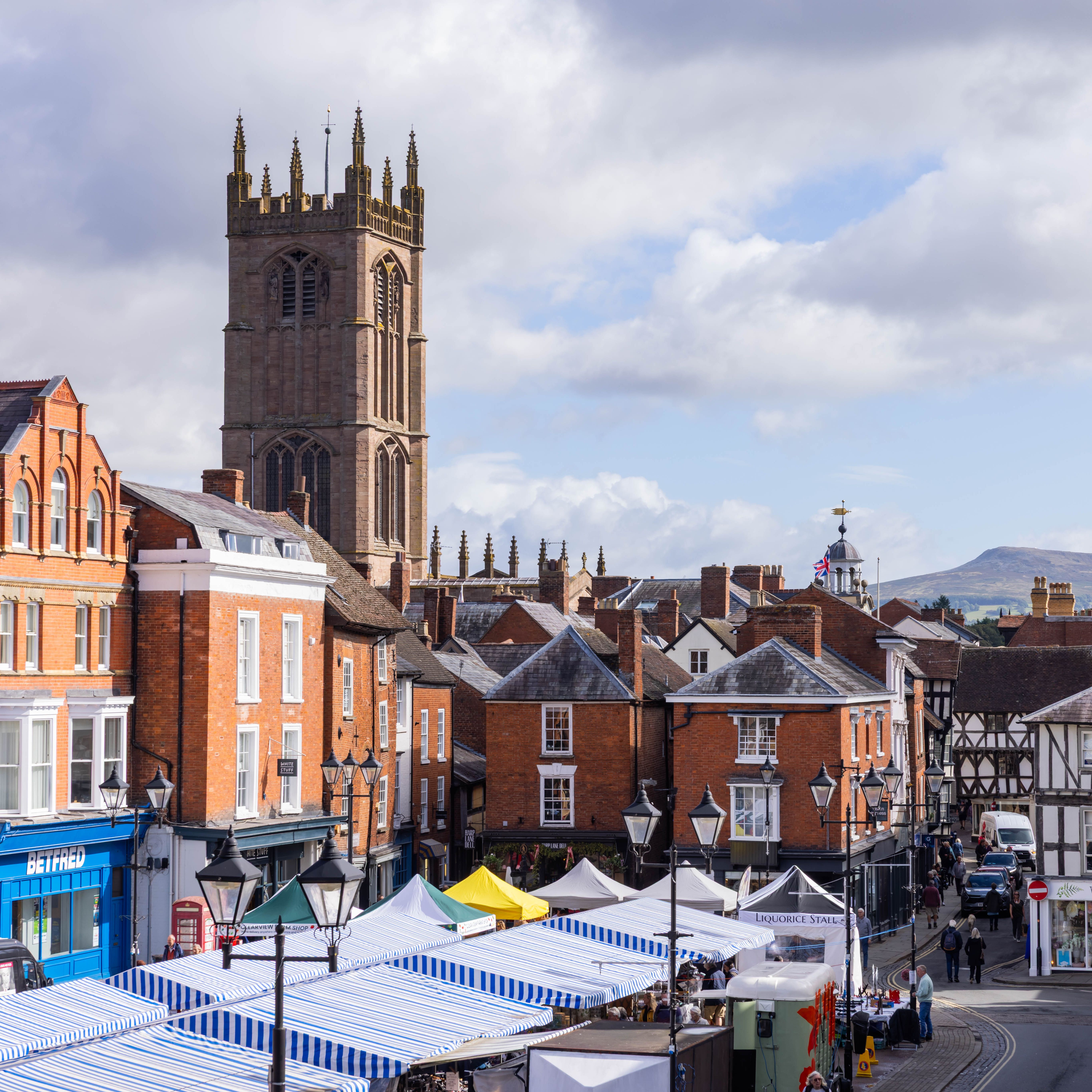 Town view of Ludlow with historic buildings, church tower, and market stalls.